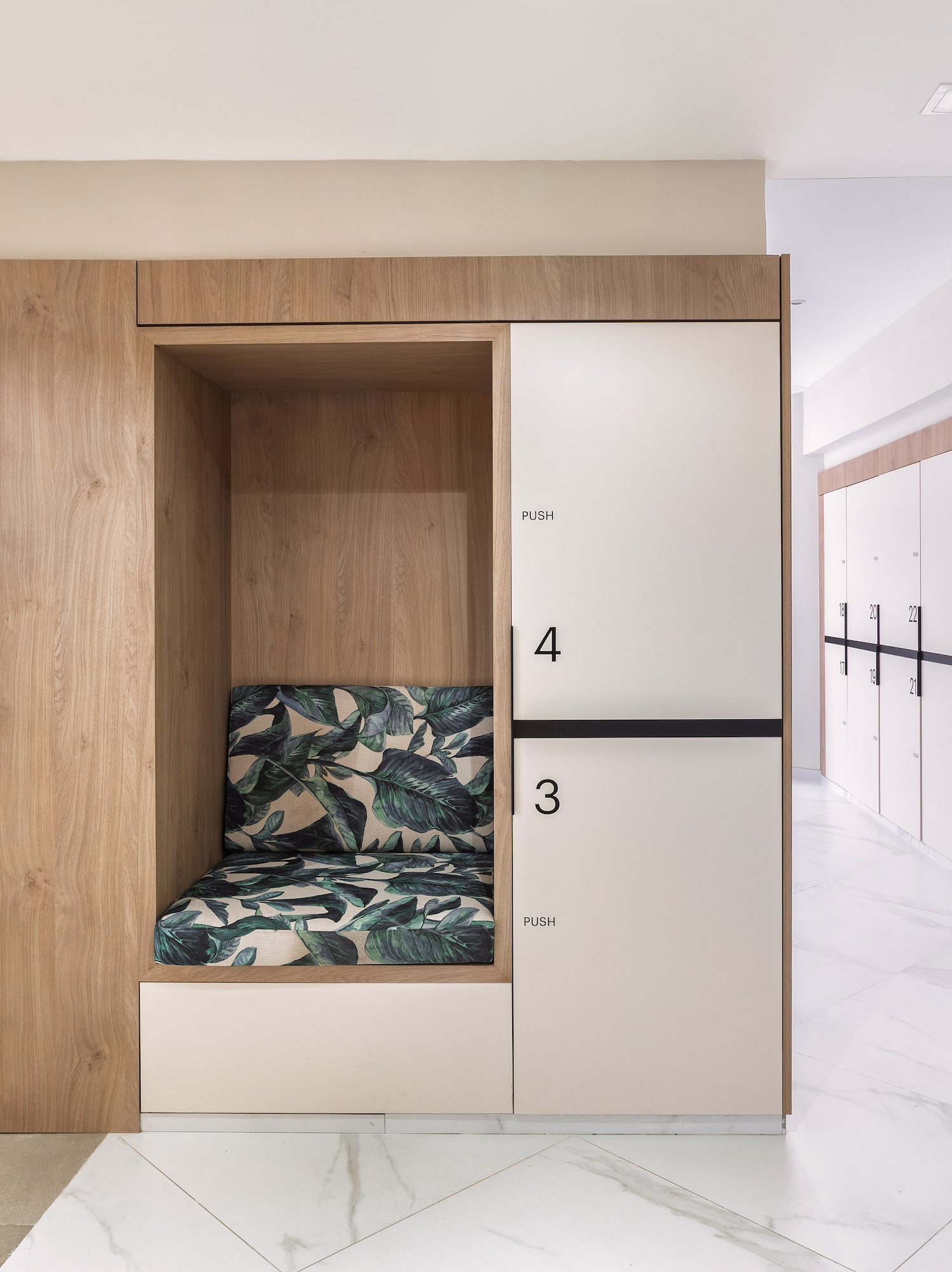 Modern changing room: wood and white numbered lockers, tropical bench.