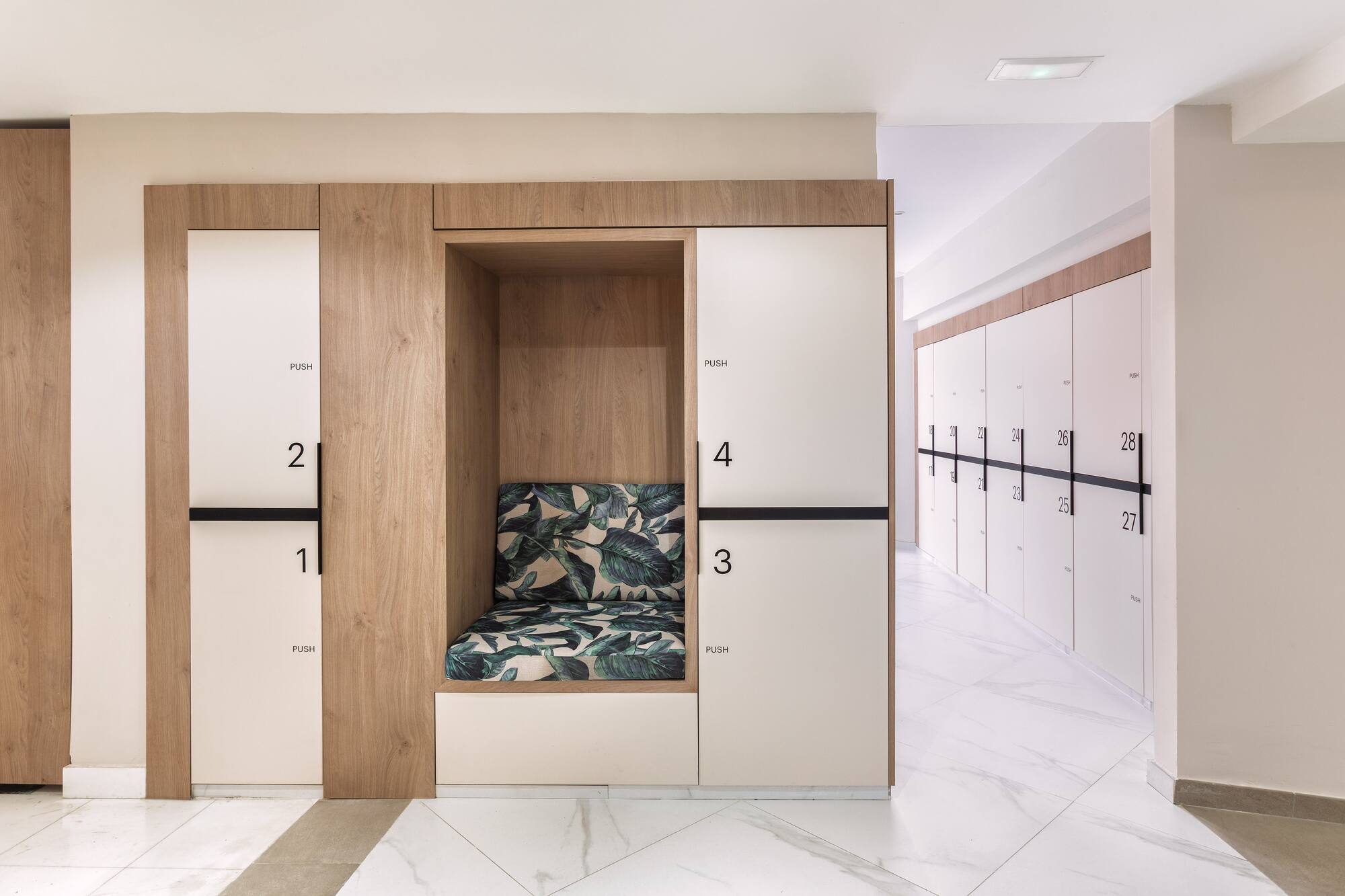 Modern wood and white lockers with numbered doors and a leafy cushion bench.