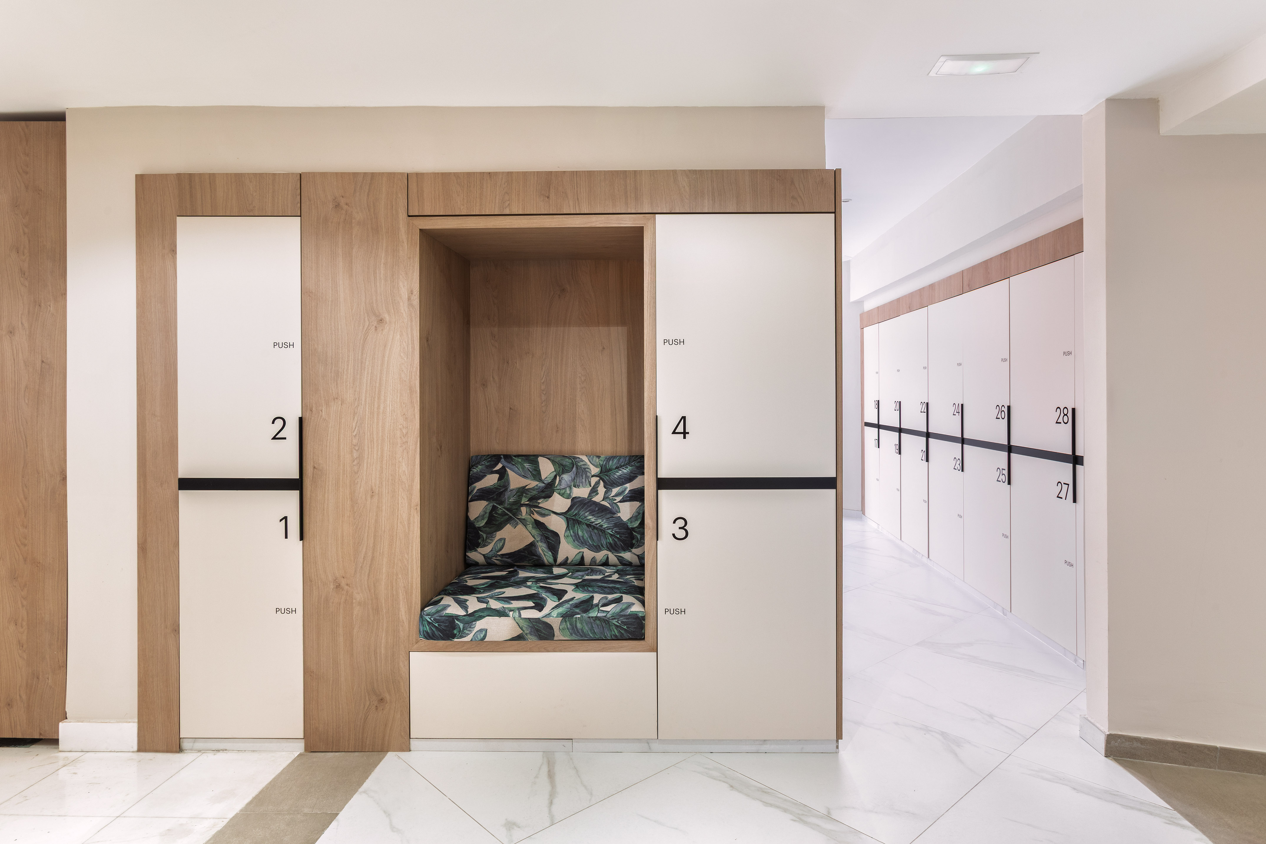 Modern changing room: wood and white numbered lockers, tropical bench.