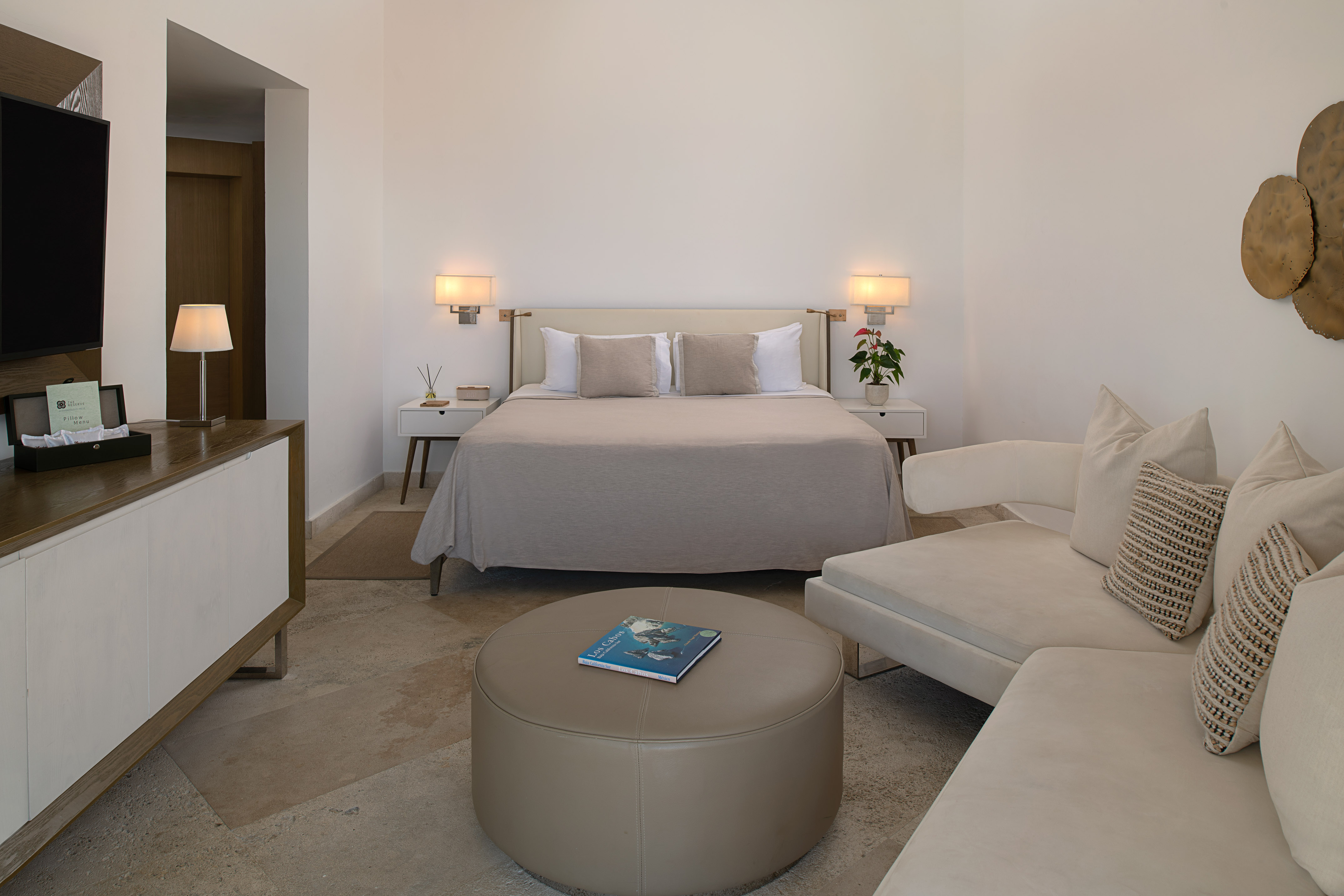 Elegant resort bedroom suite with king bed, chaise lounge, and stylish ottoman.