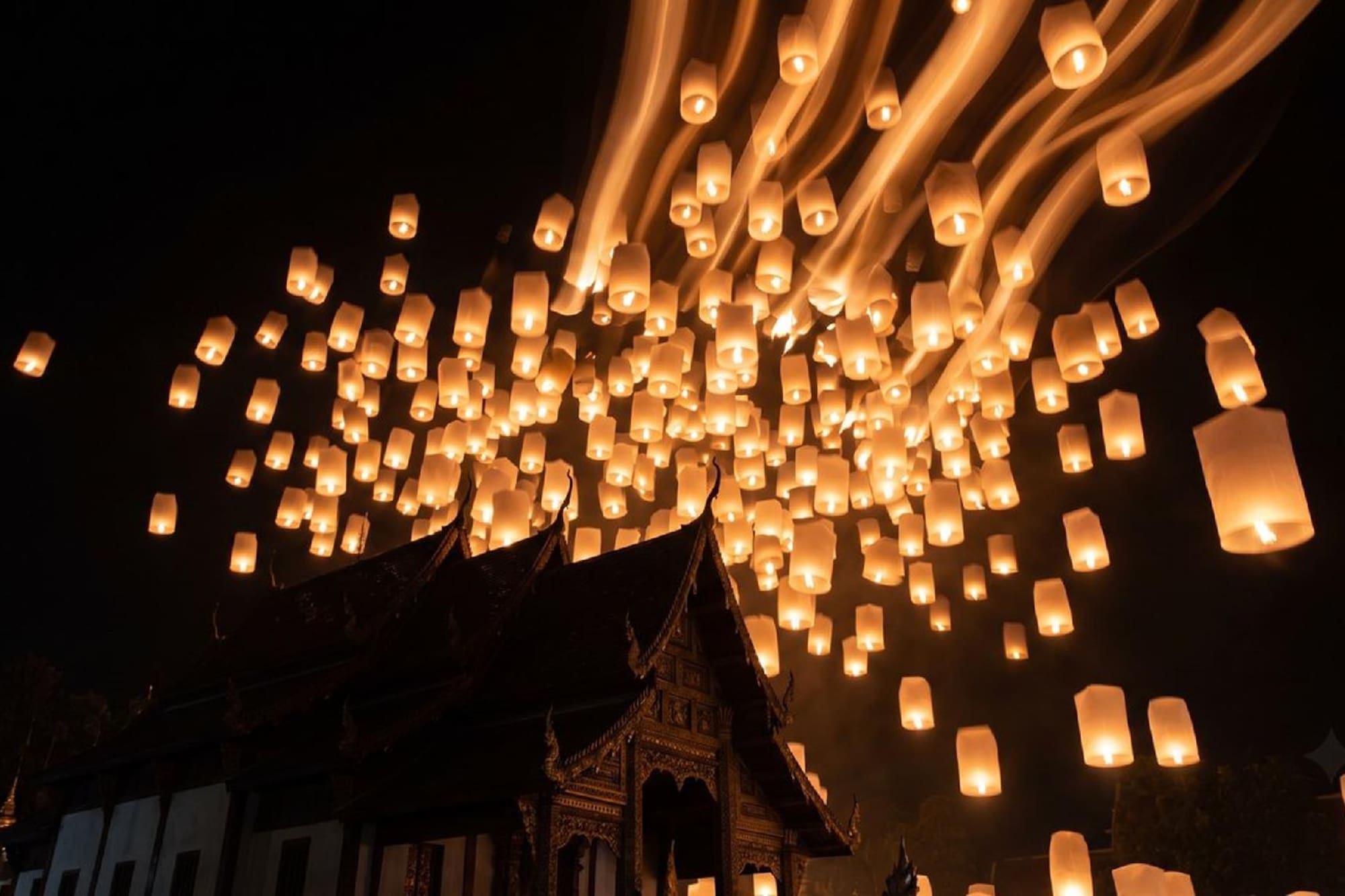 Yi Peng festival: hundreds of glowing sky lanterns float above a Thai temple.