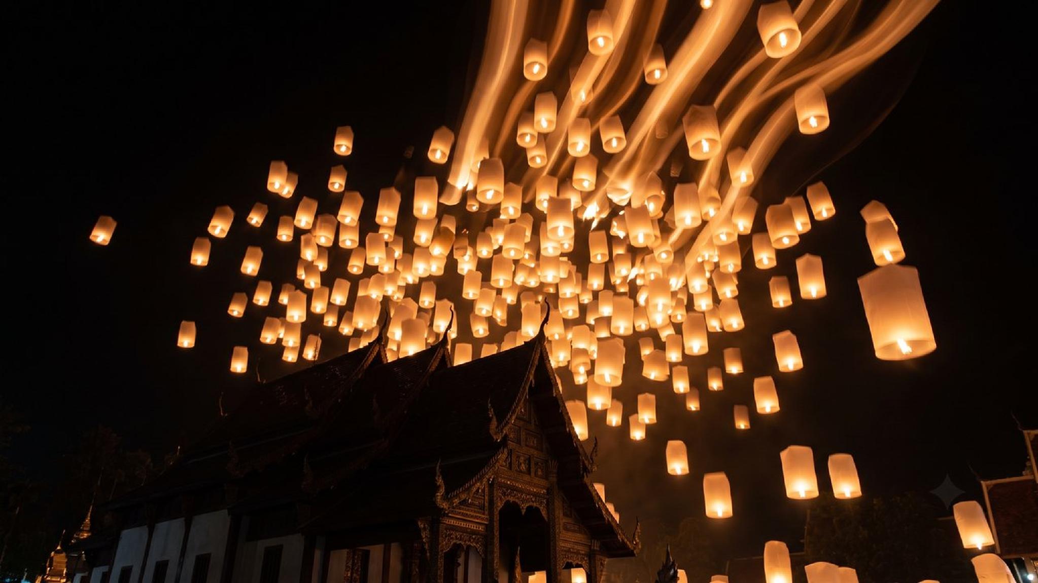 Yi Peng festival: hundreds of glowing sky lanterns float above a Thai temple.