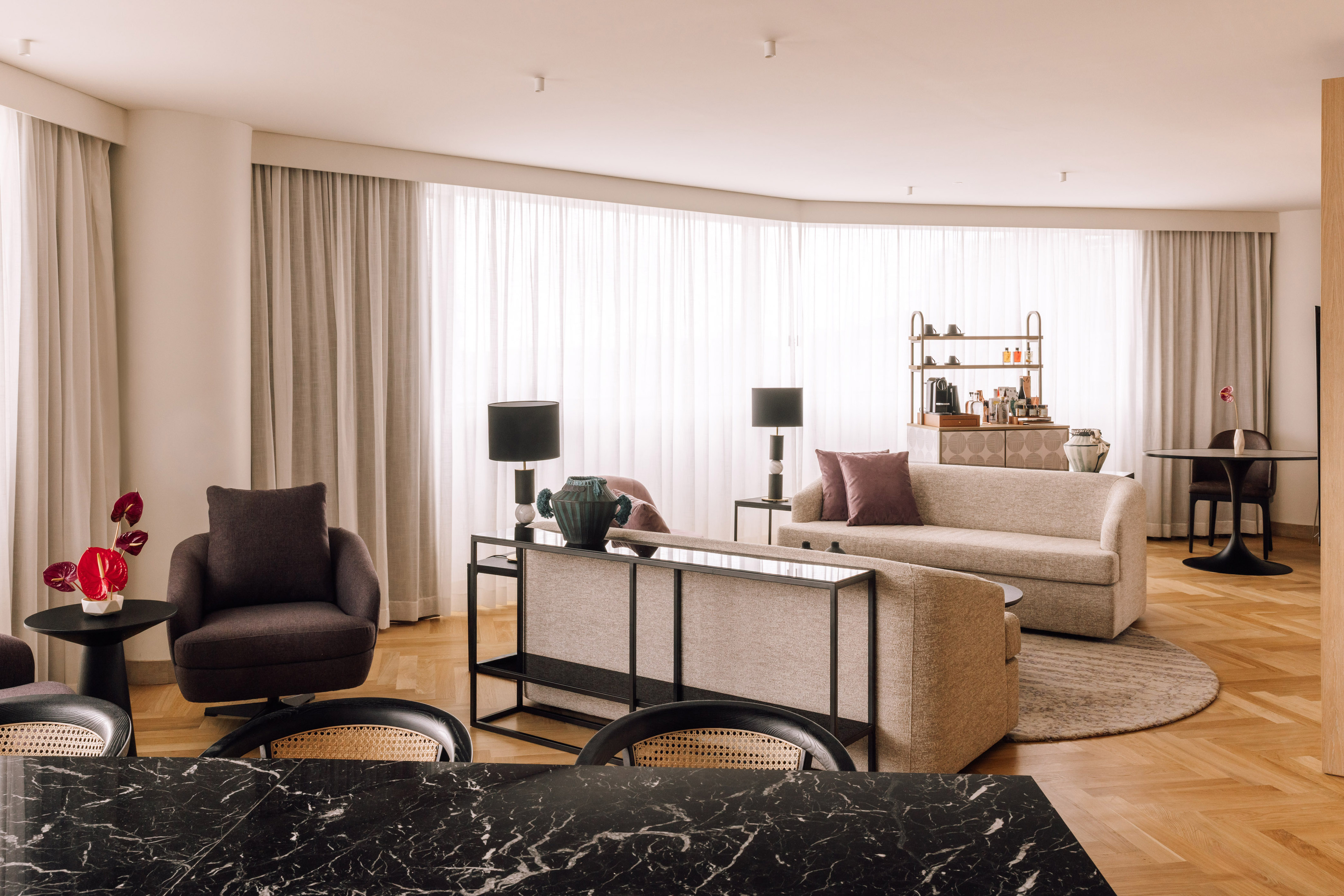 Luxury living room with modern sofa, armchairs, marble table, and sheer curtains.