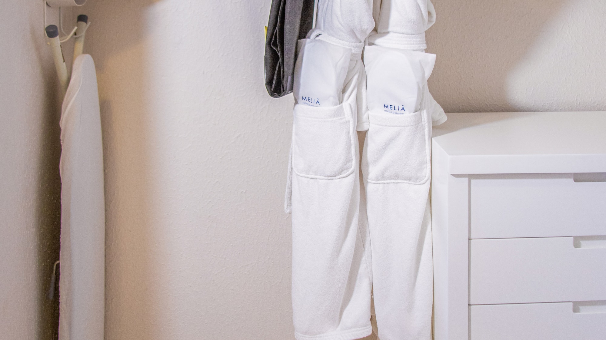 Hotel closet: iron, ironing board, Melia bathrobes, hangers, wall safe, drawers.