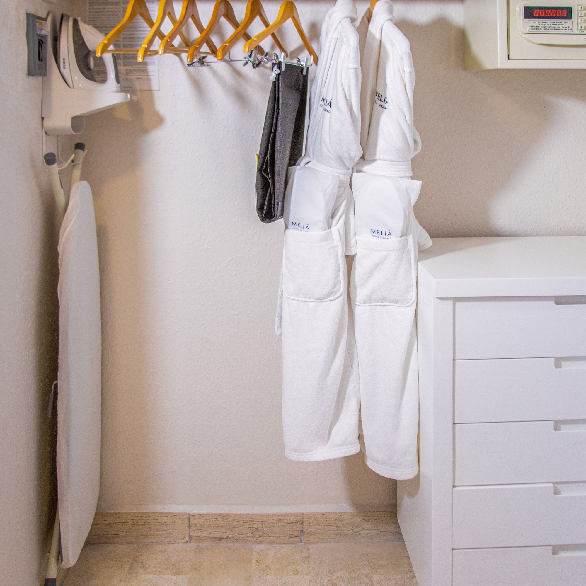 Hotel closet: iron, ironing board, Melia bathrobes, hangers, wall safe, drawers.