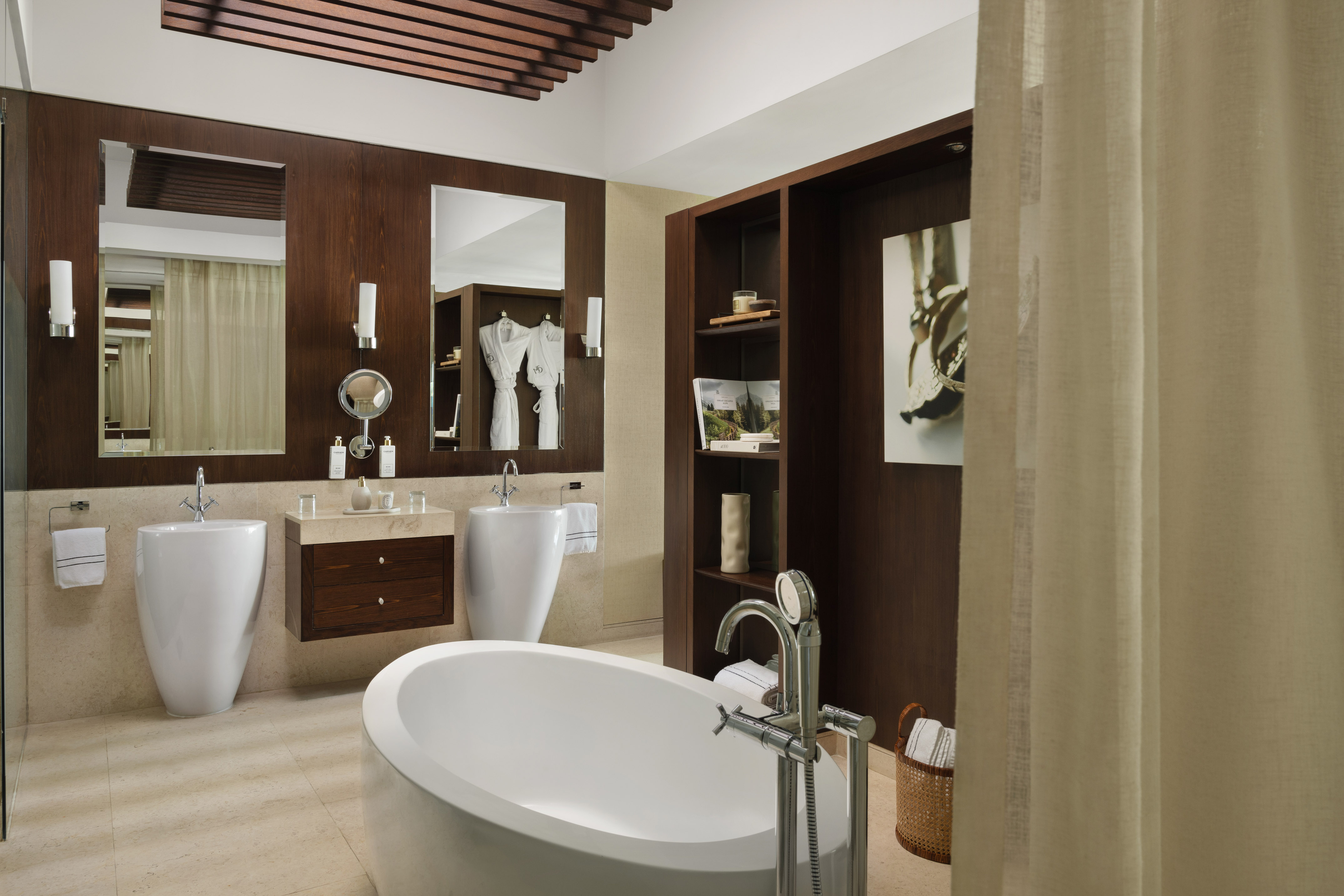 Modern bathroom with freestanding bathtub, dual sinks, and dark wood paneling.
