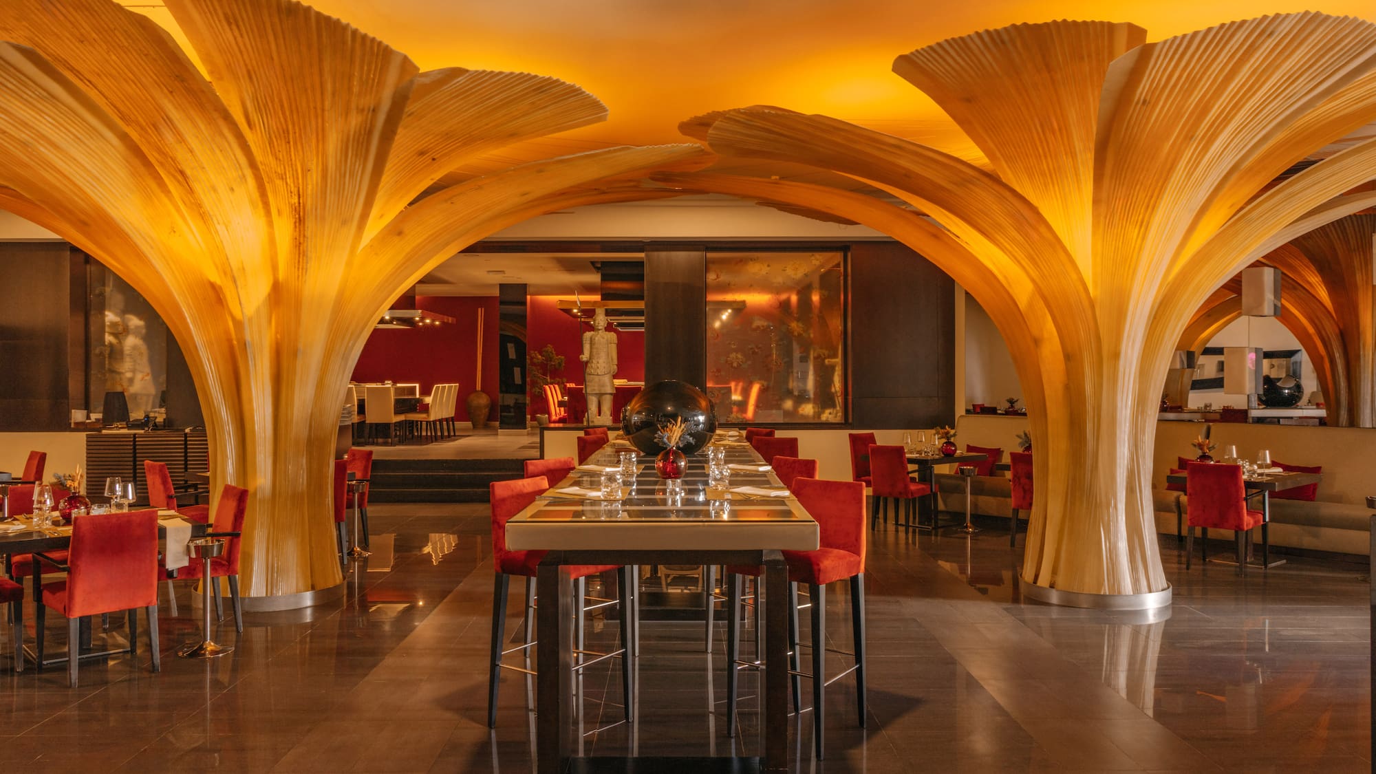 Upscale restaurant with natural wood arches, warm lighting, and red seating.