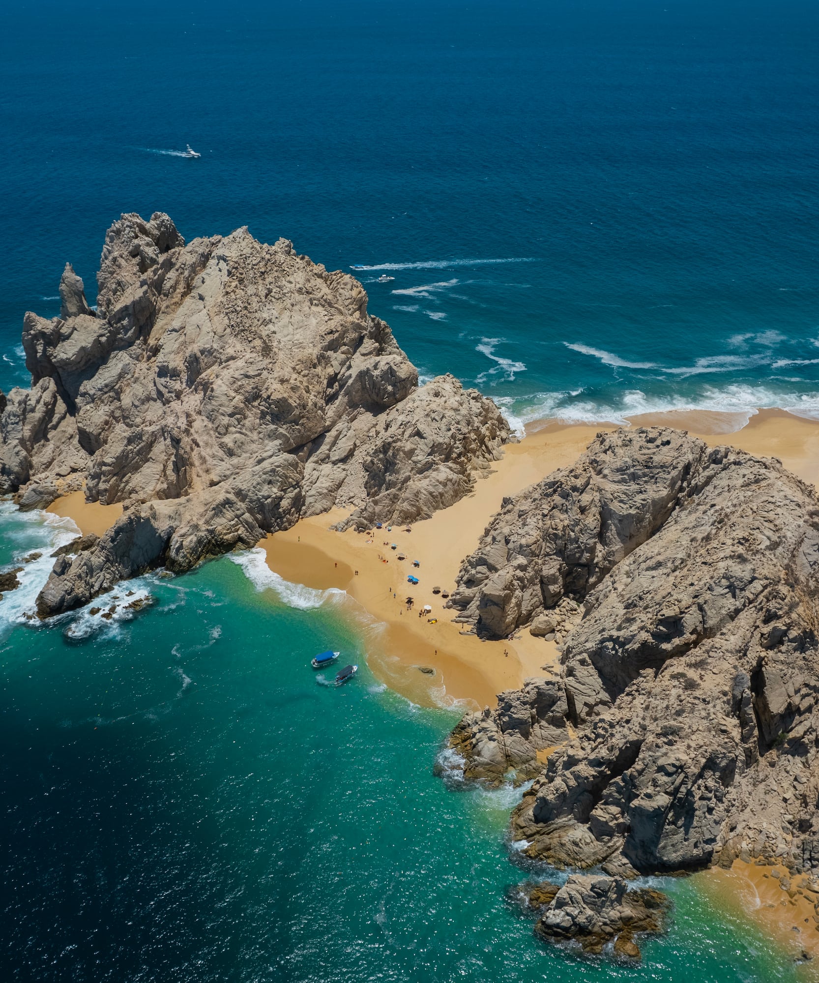 a rocky beach with blue water and boats