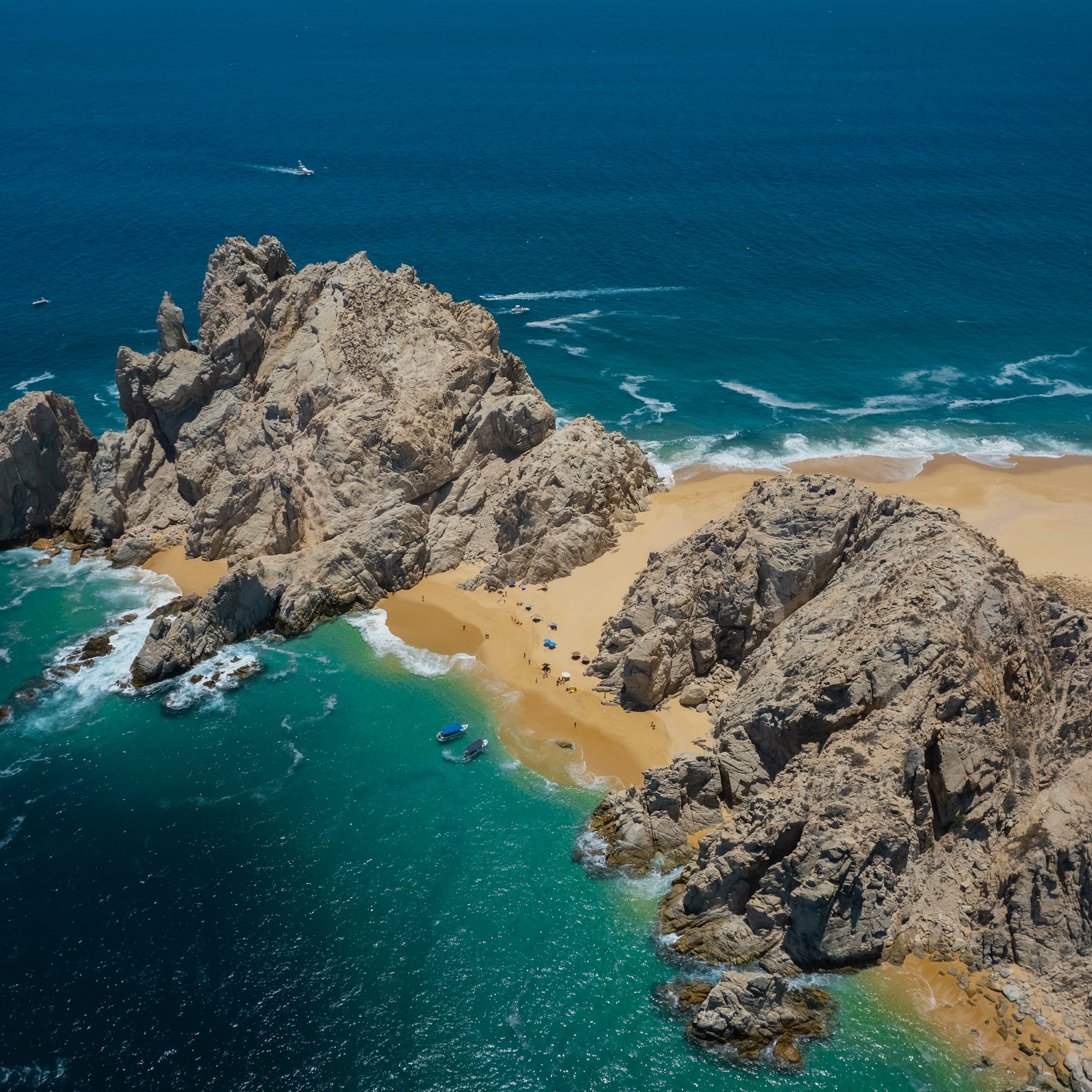 a rocky beach with blue water and boats