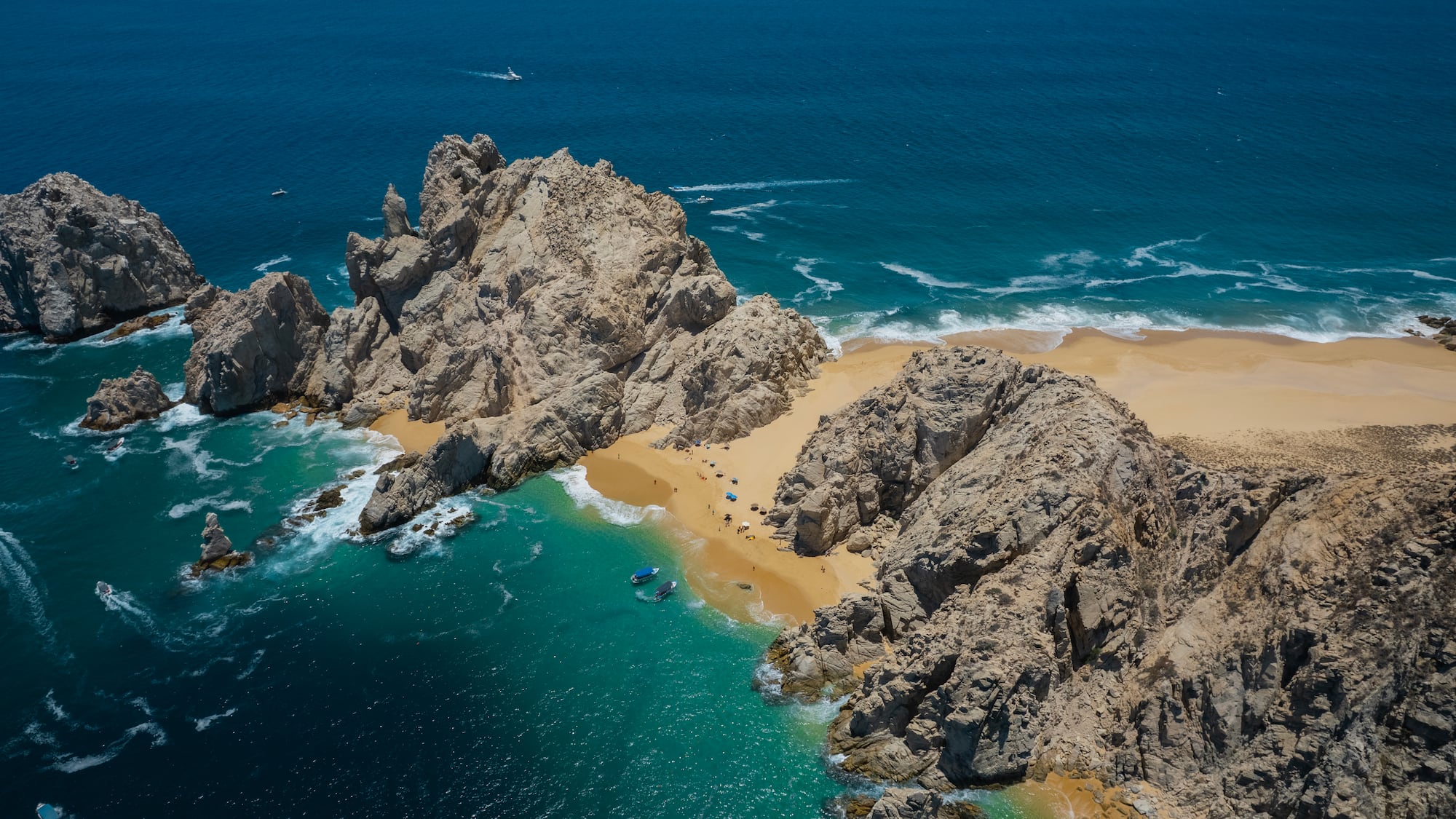 a rocky beach with blue water and boats