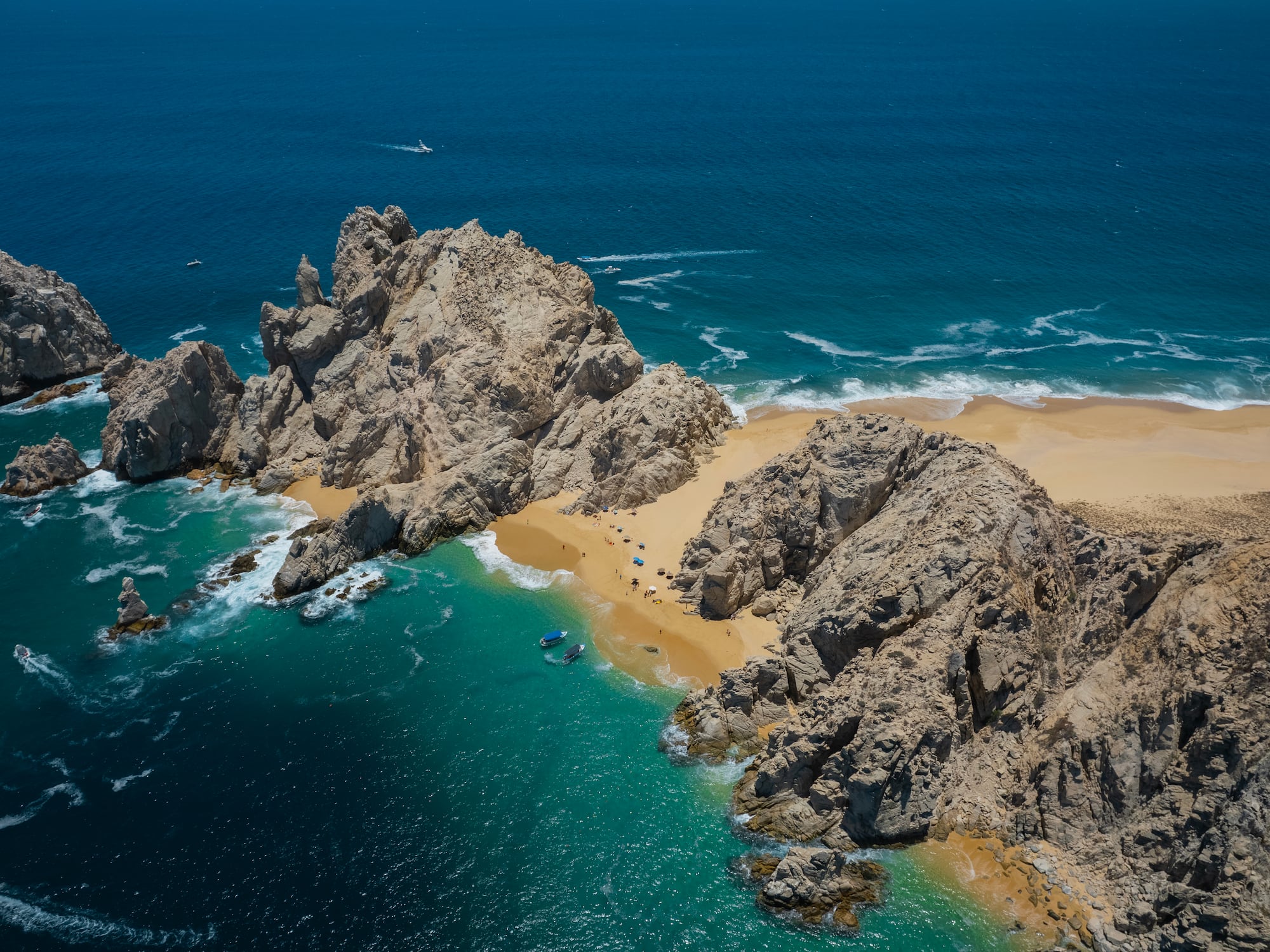 a rocky beach with blue water and boats