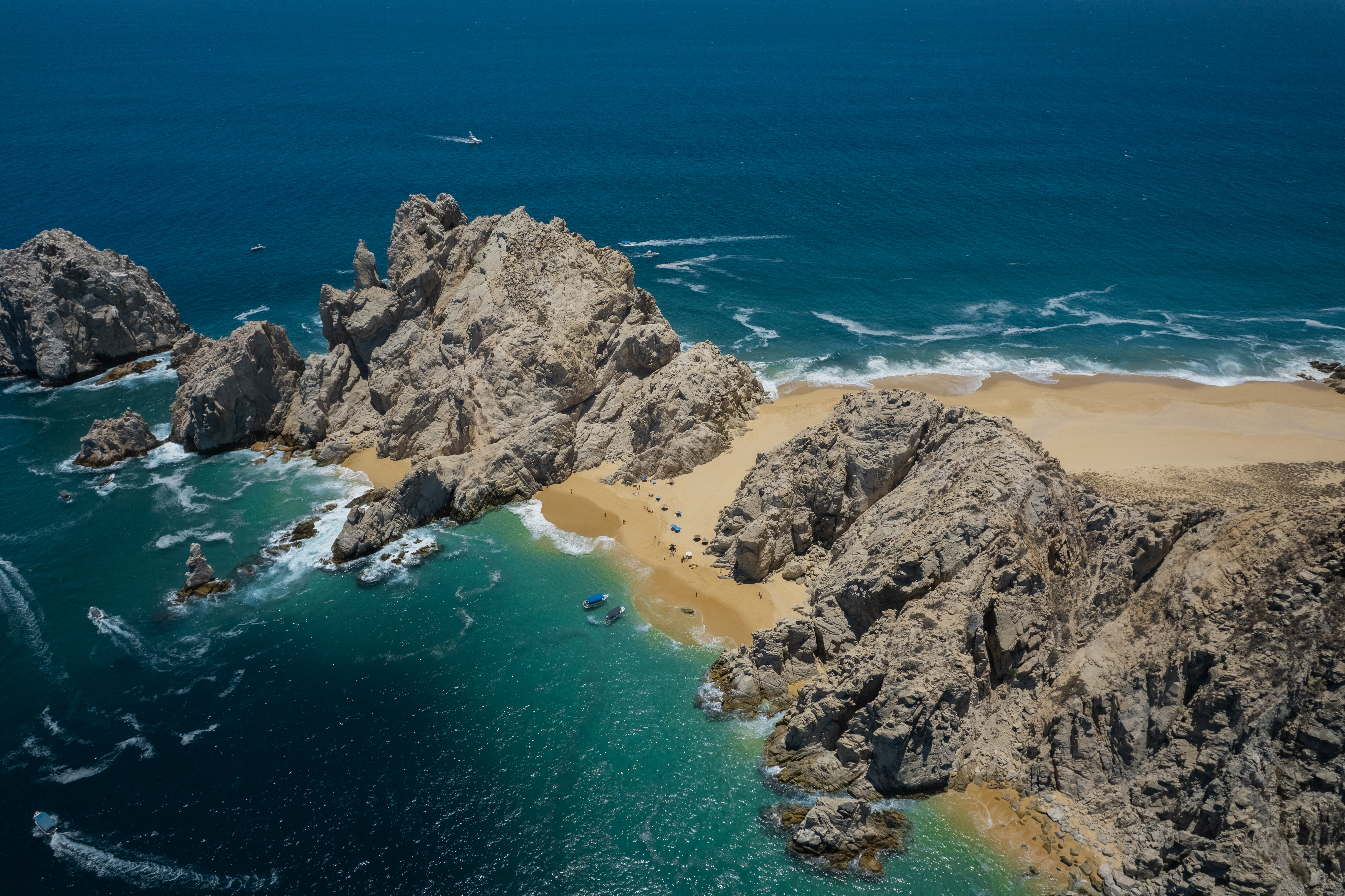 a rocky beach with blue water and boats