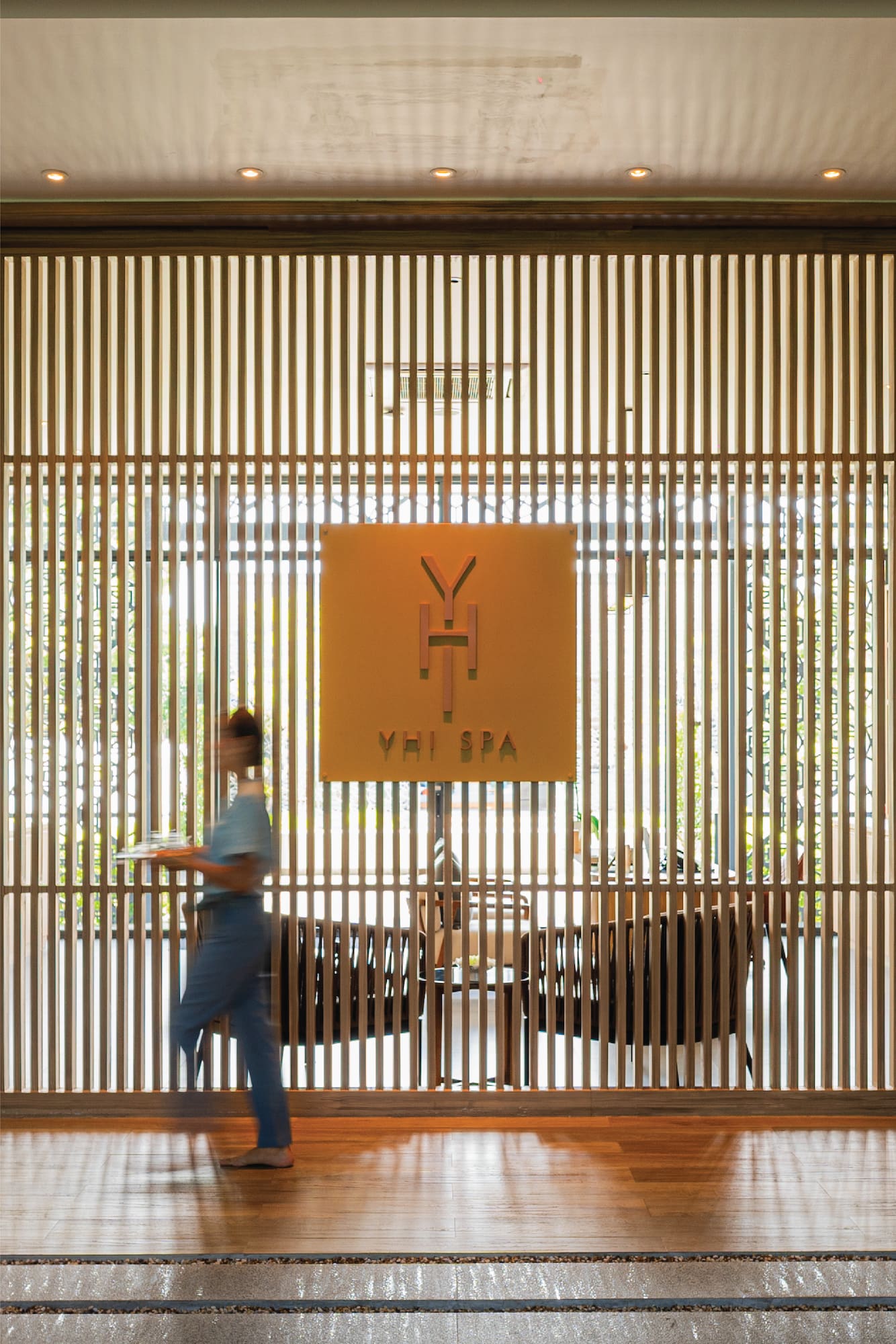 a woman walking in front of a wooden wall