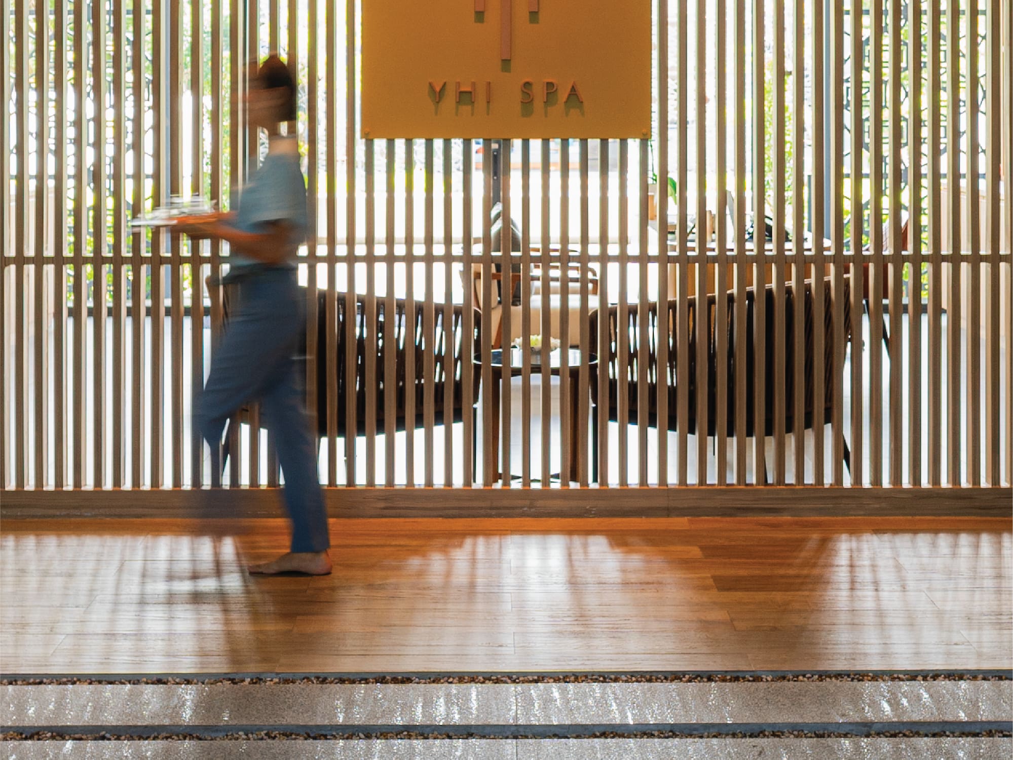 a woman walking in front of a wooden wall