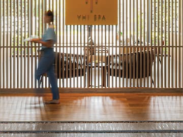 a woman walking in front of a wooden wall