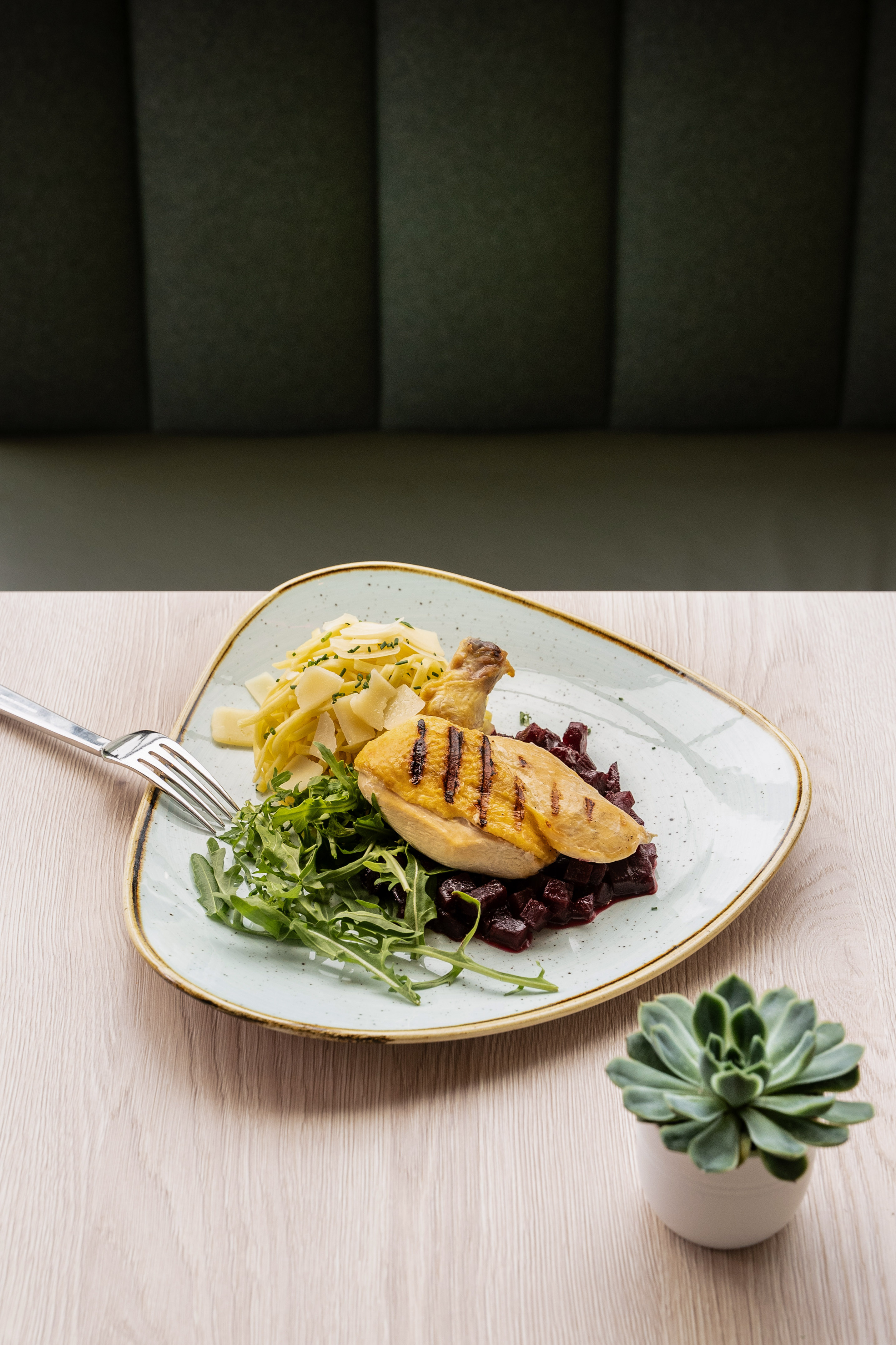 Plate of grilled chicken, pasta, diced beetroot, and arugula salad.