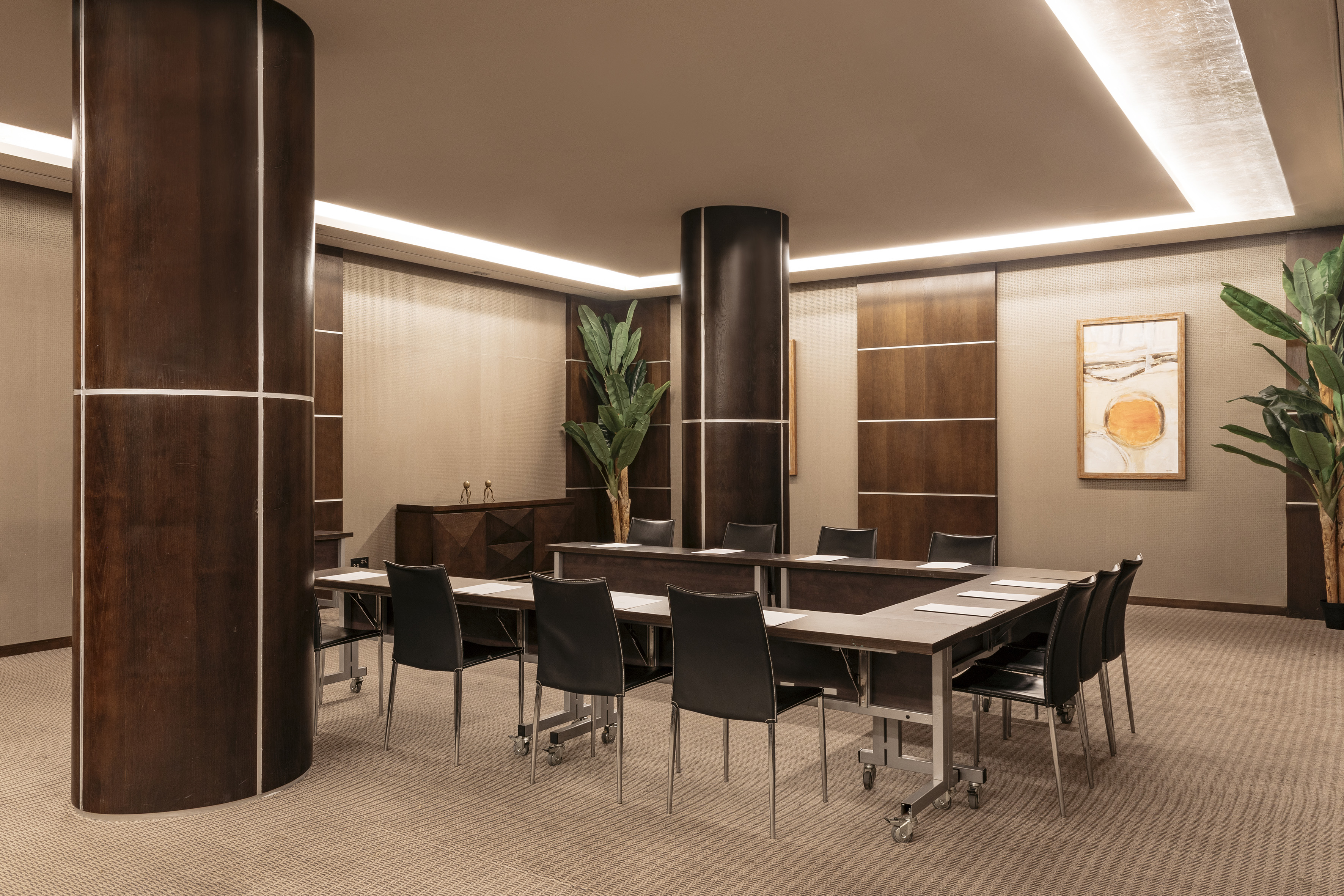 Modern conference room, U-shaped table, black chairs, dark wood design.