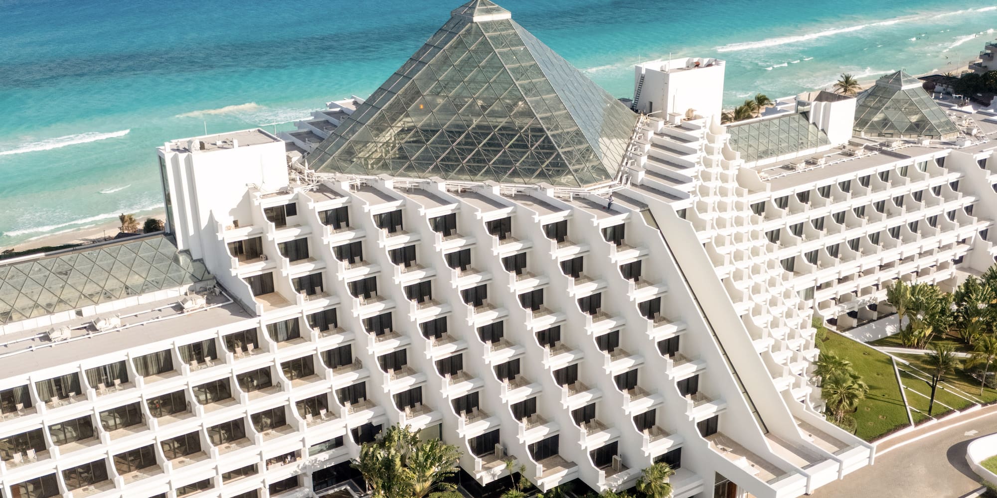 Cancun pyramid luxury hotel on turquoise beach, aerial view.
