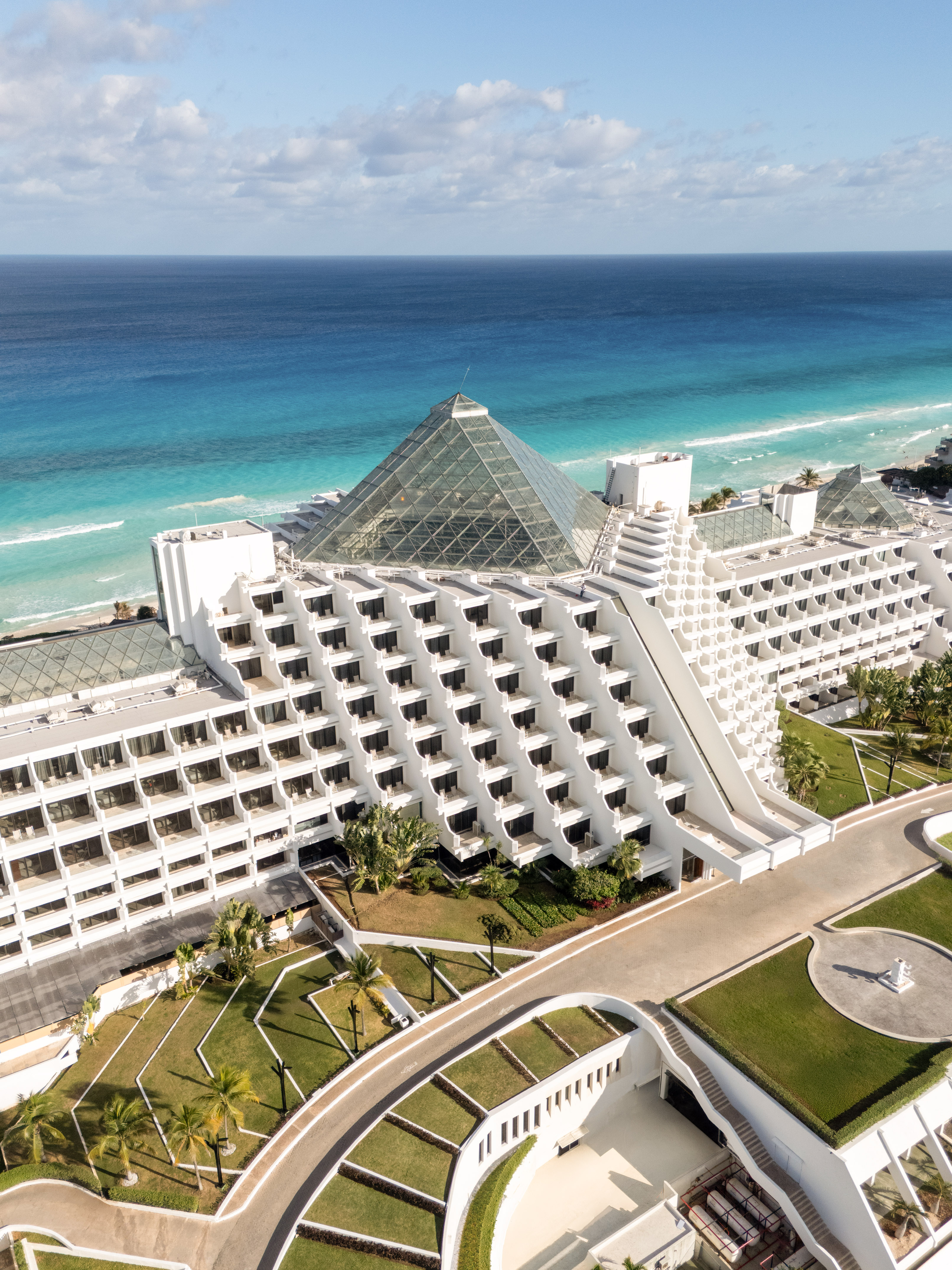 Cancun pyramid luxury hotel on turquoise beach, aerial view.