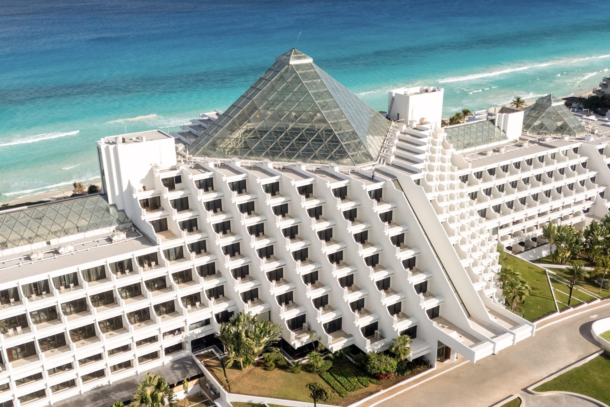 Cancun pyramid luxury hotel on turquoise beach, aerial view.