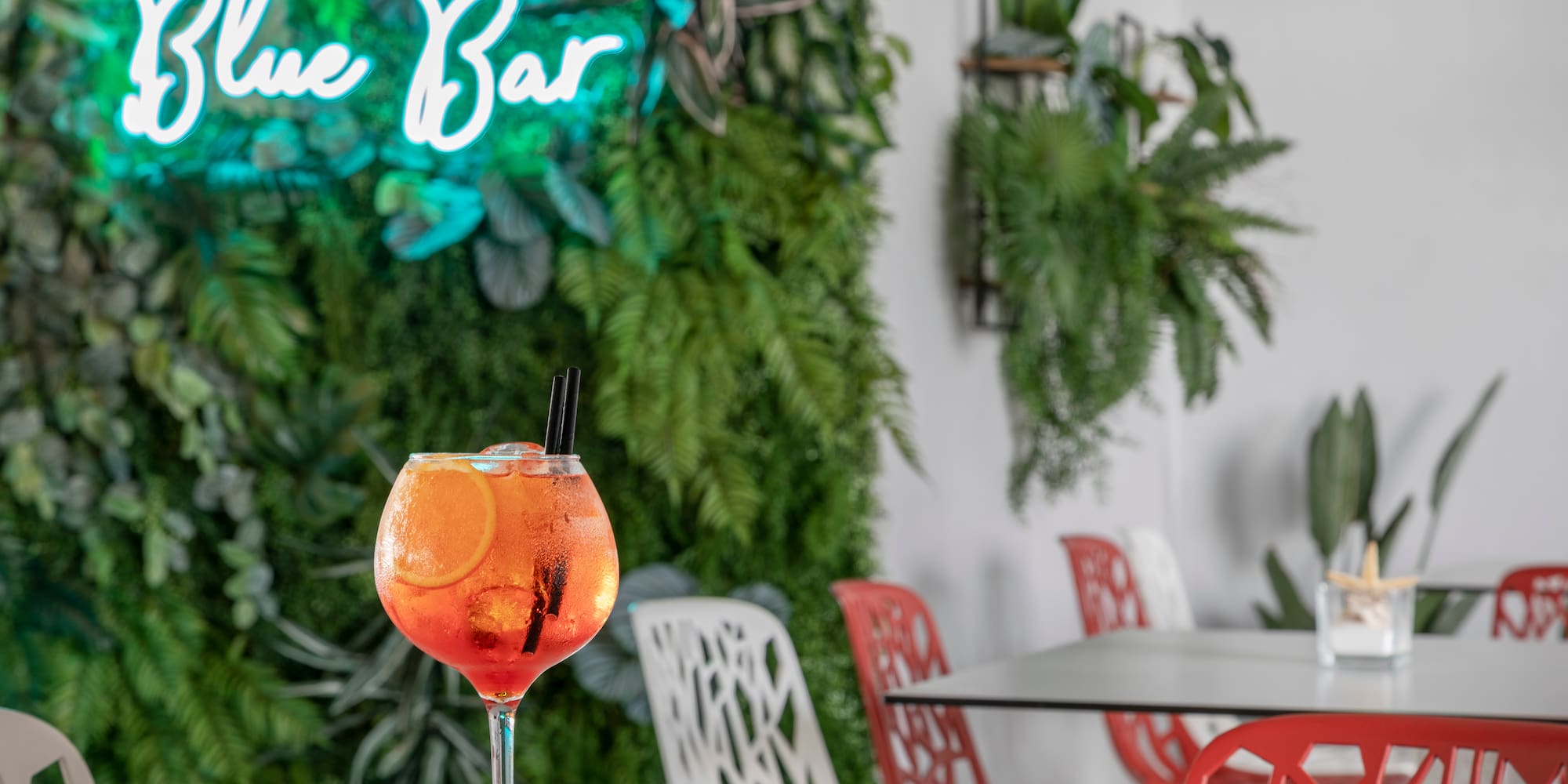 a glass of orange liquid with ice and orange slices on a table