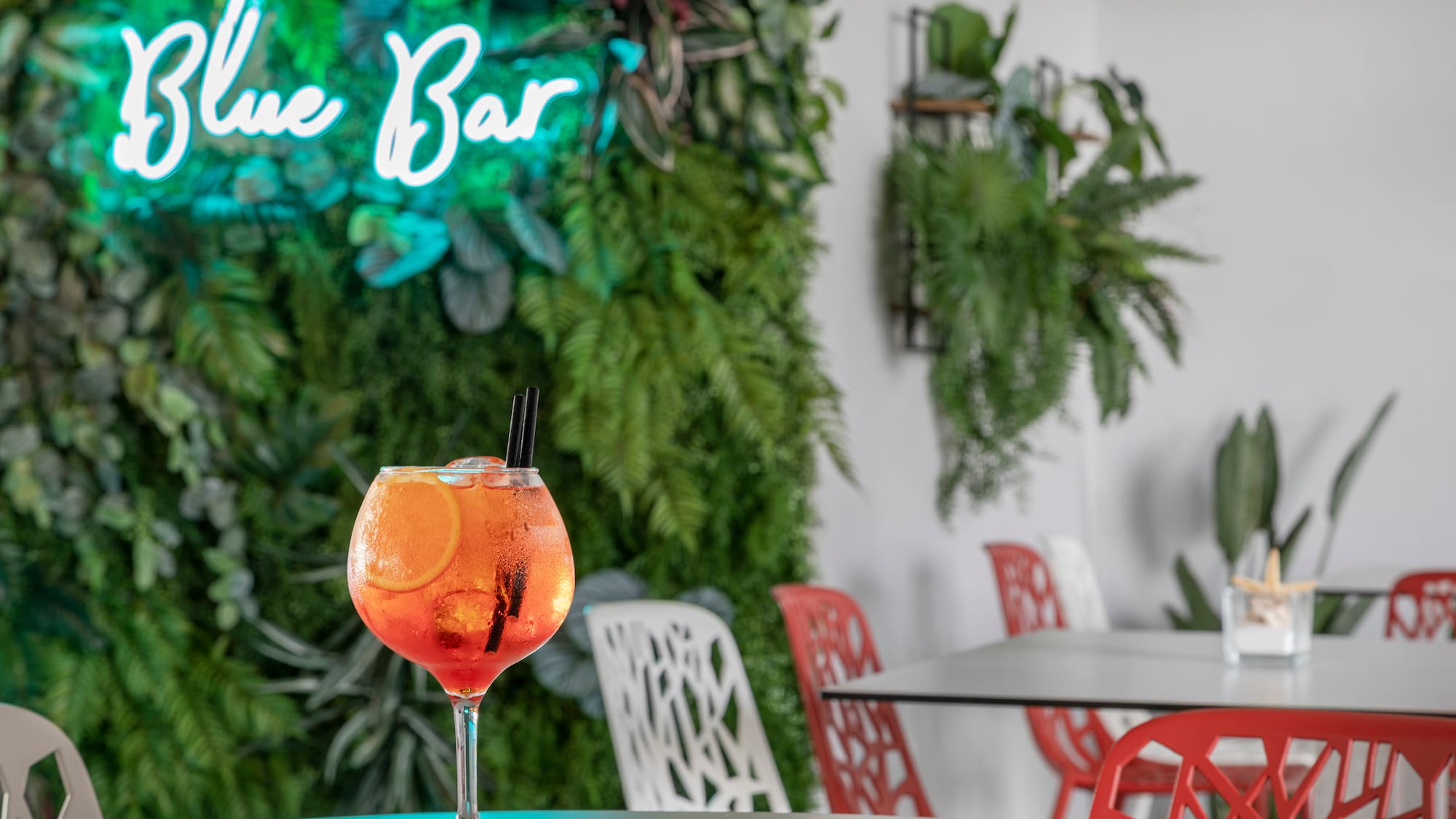 a glass of orange liquid with ice and orange slices on a table