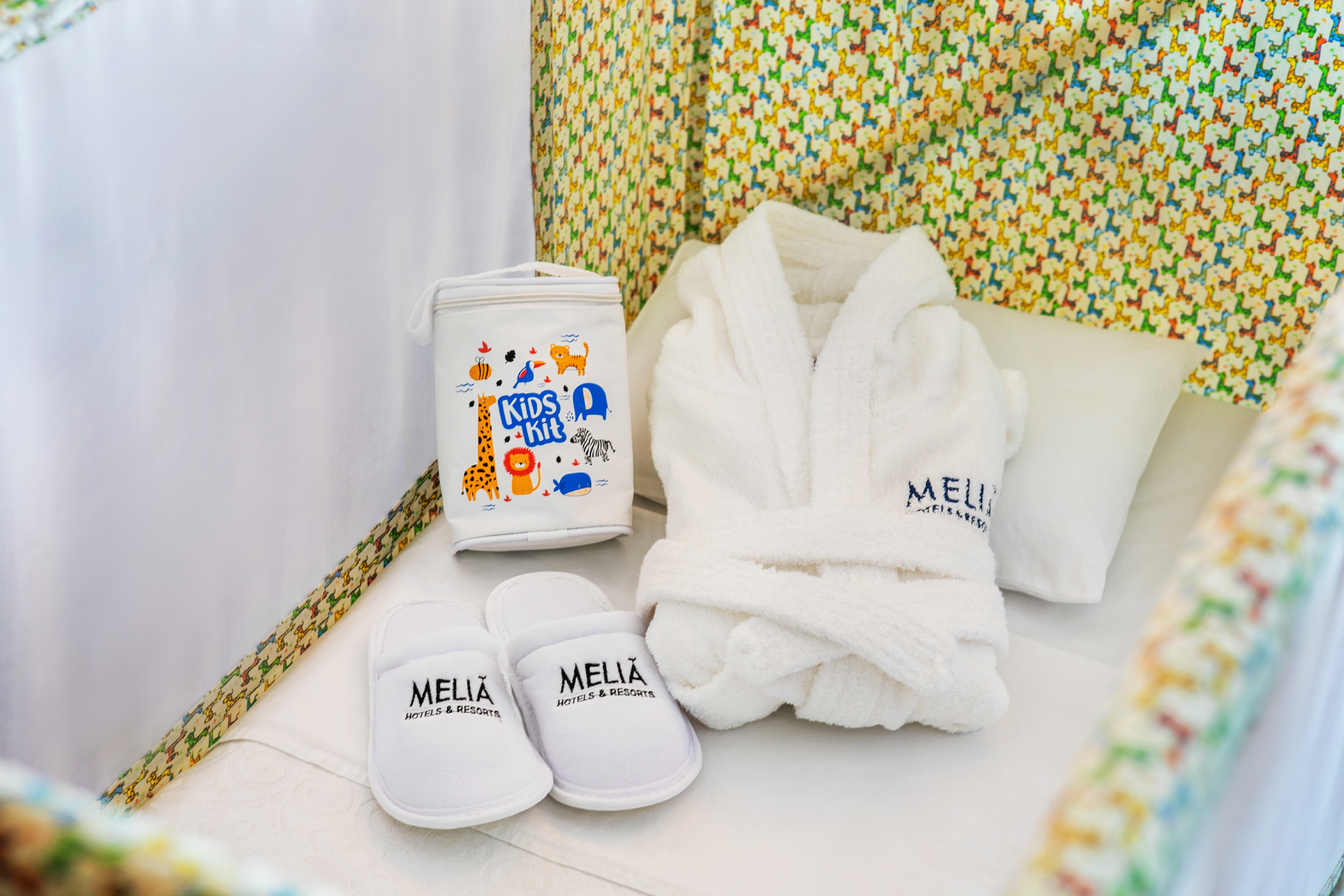Meliá Kids Kit, bathrobe, slippers in hotel baby crib with animal pattern.