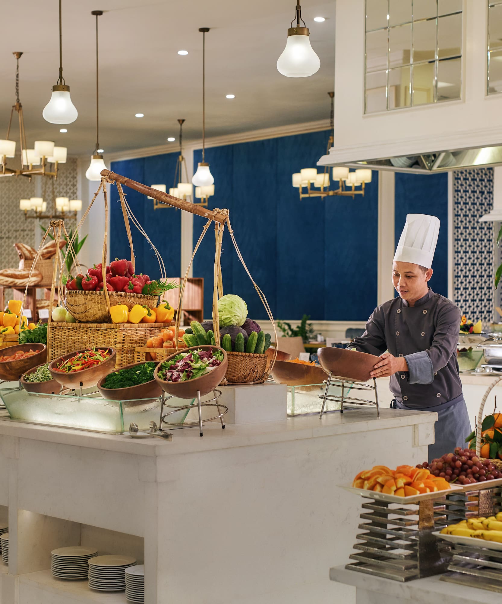 a chef standing behind a counter with fruits