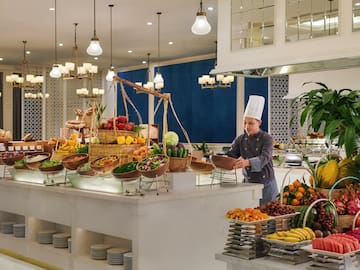 a chef standing behind a counter with fruits