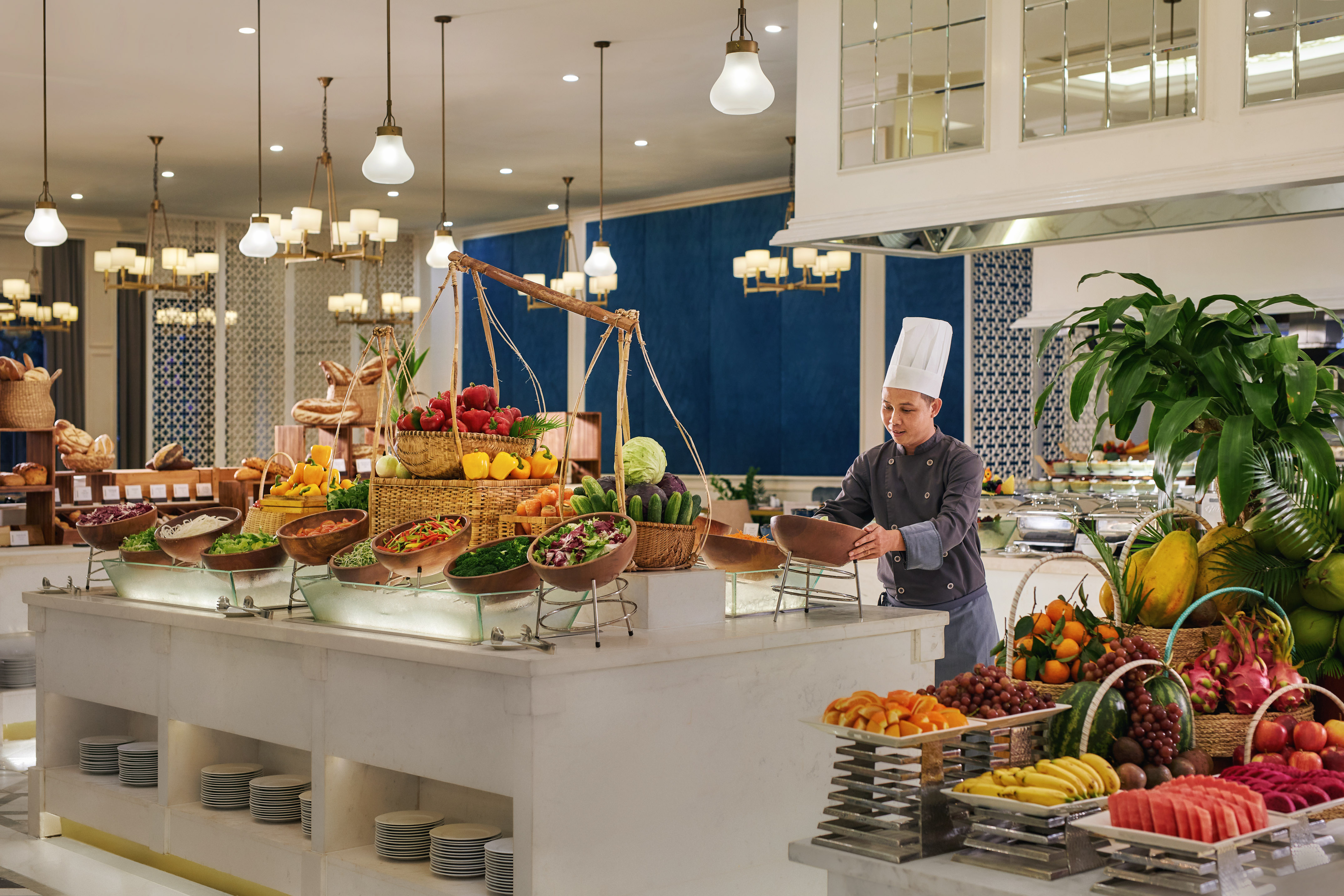 Chef at a hotel buffet with fresh fruit, salad bar, vegetables, and bread.