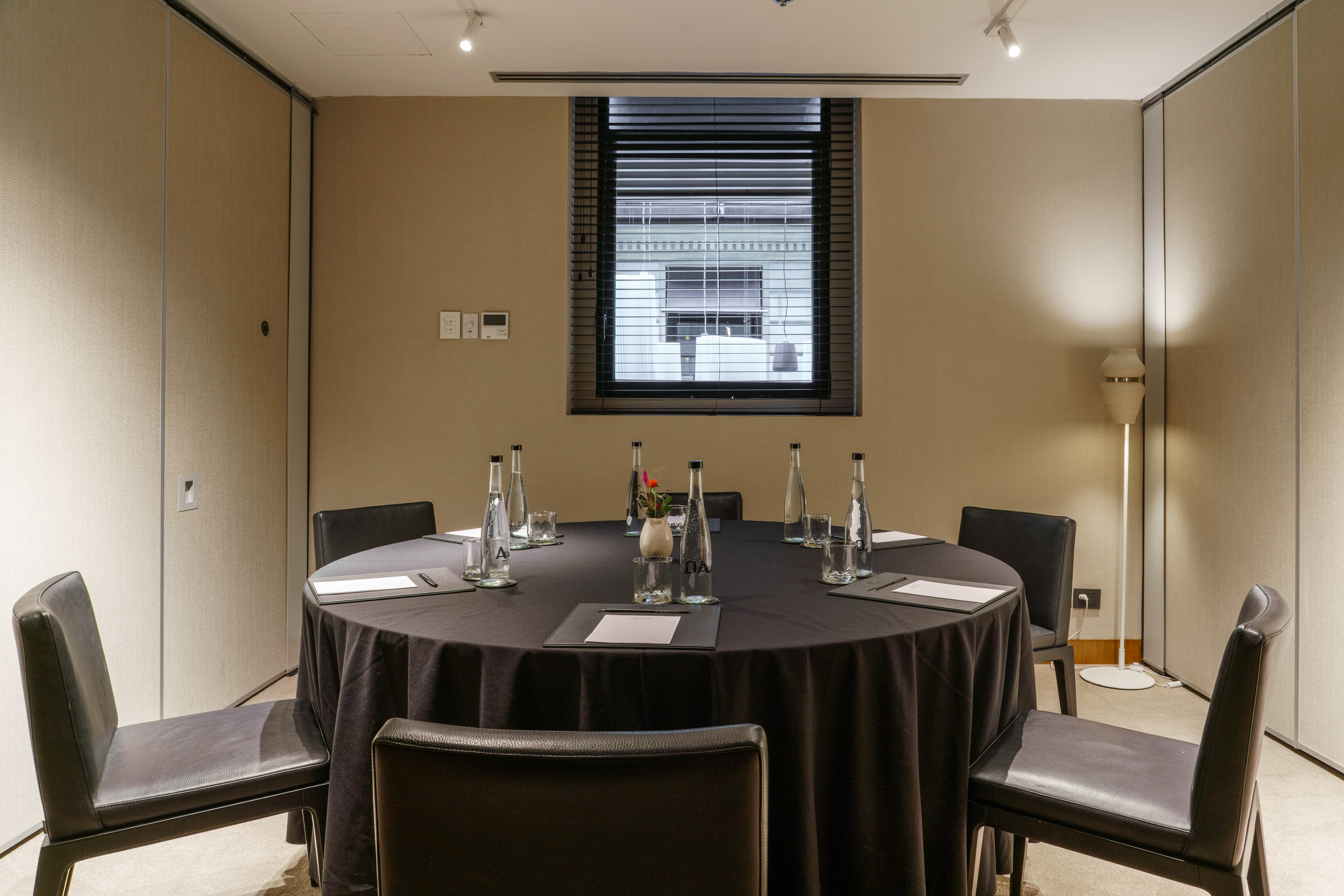 Modern conference room with round table, black chairs, and window.