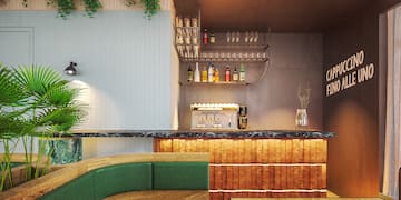 a bar with a shelf of wine glasses and a green couch