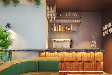 a bar with a shelf of wine glasses and a green couch