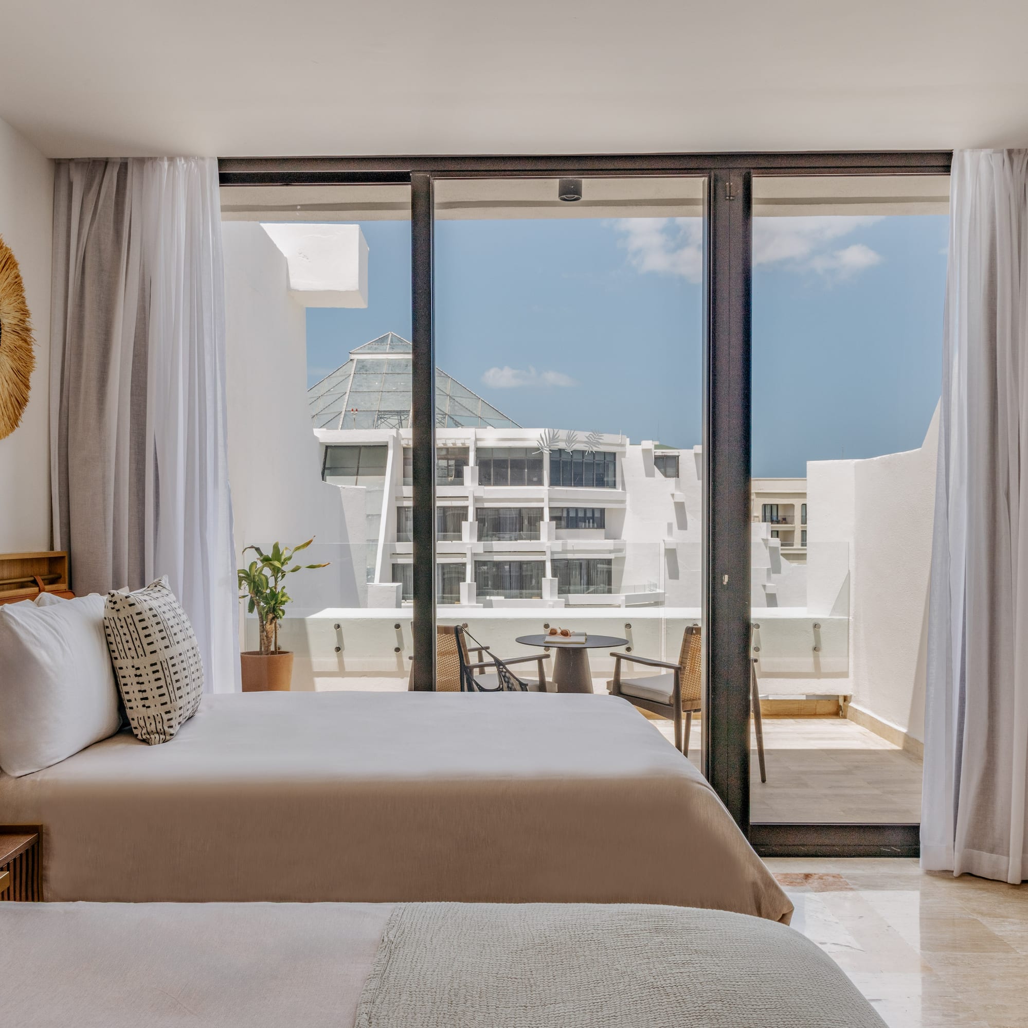 Modern hotel bedroom with balcony, outdoor seating, and resort view.