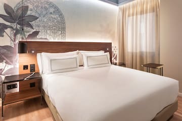 a bed with white sheets and a wood headboard