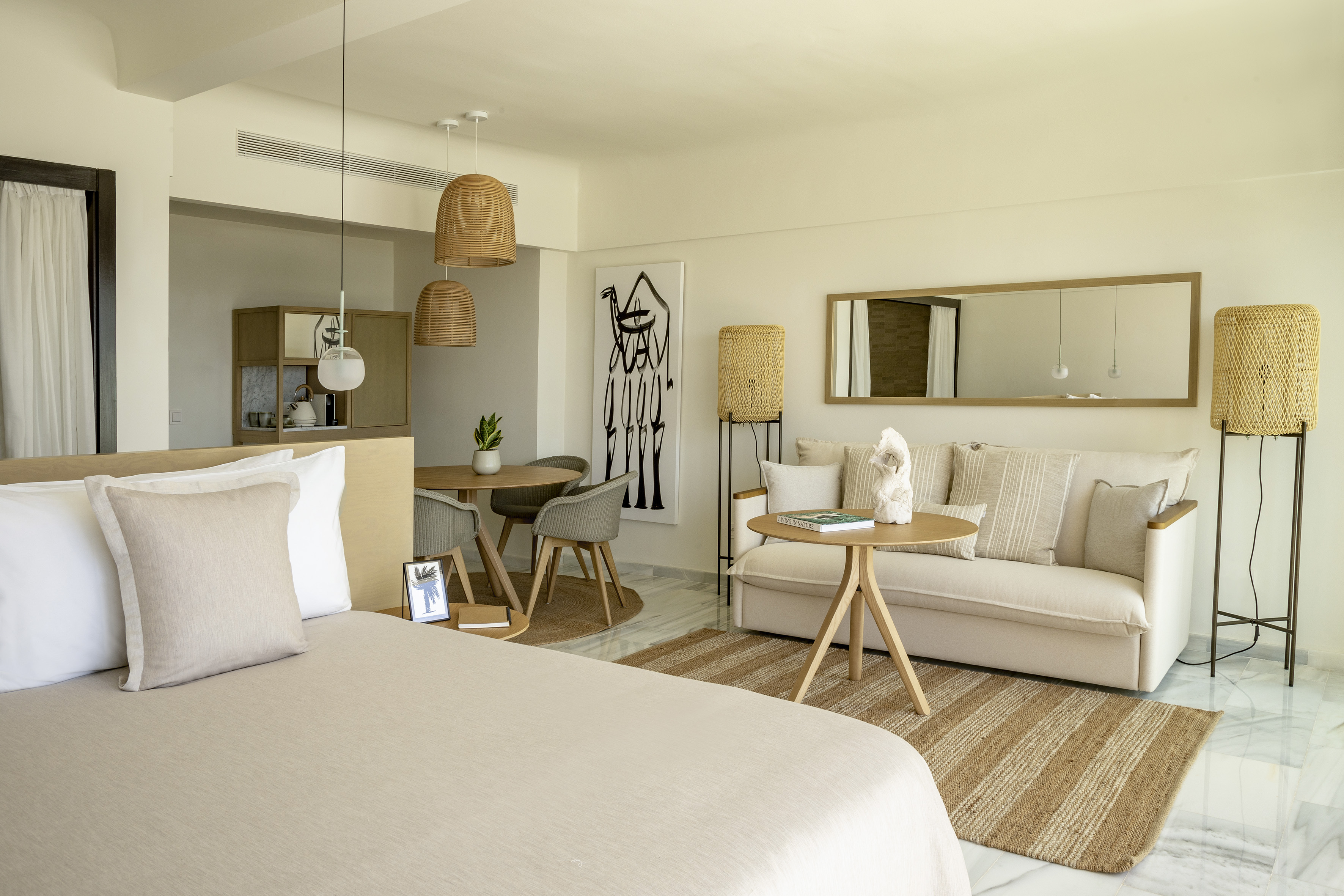 Modern open-plan suite, neutral decor, bed, sofa, dining, natural textures.