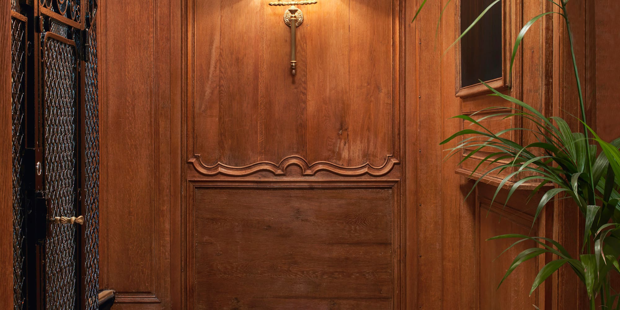a wood paneled wall with a lamp and a plant in a pot