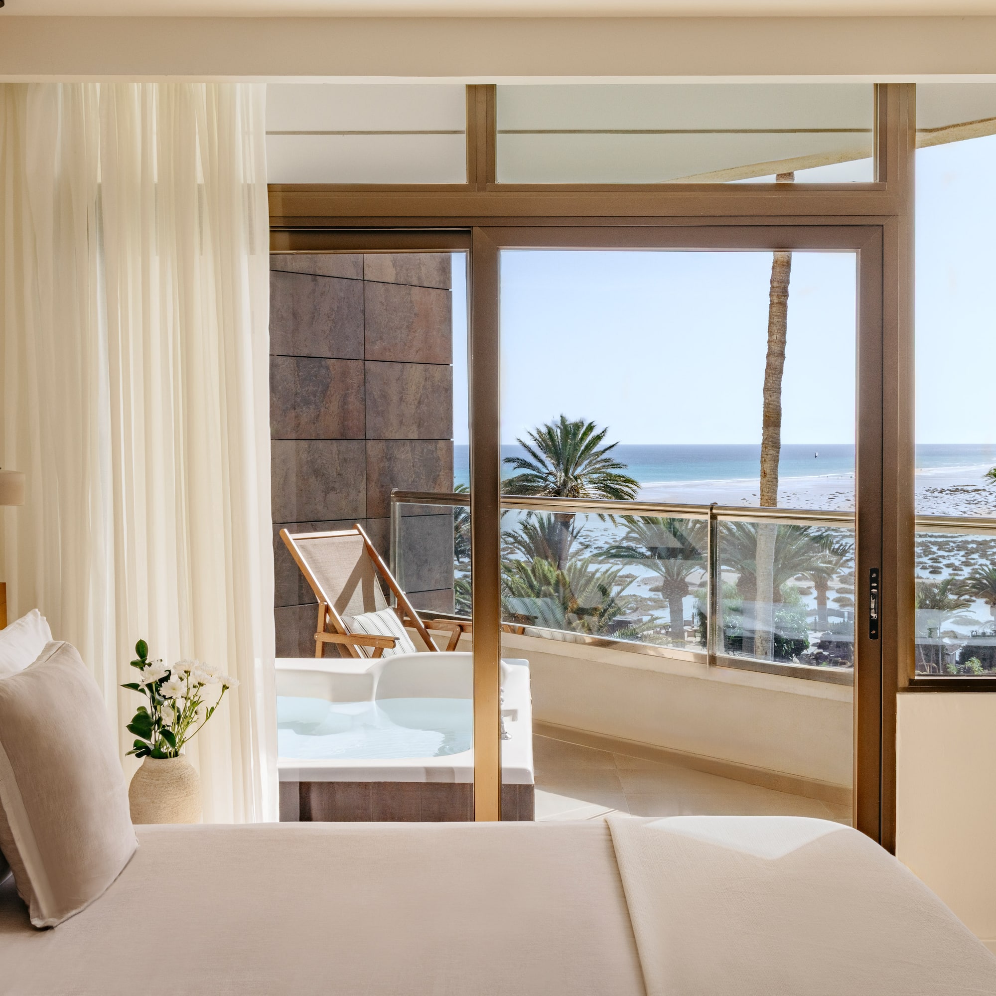 a bedroom with a view of the ocean and a jacuzzi