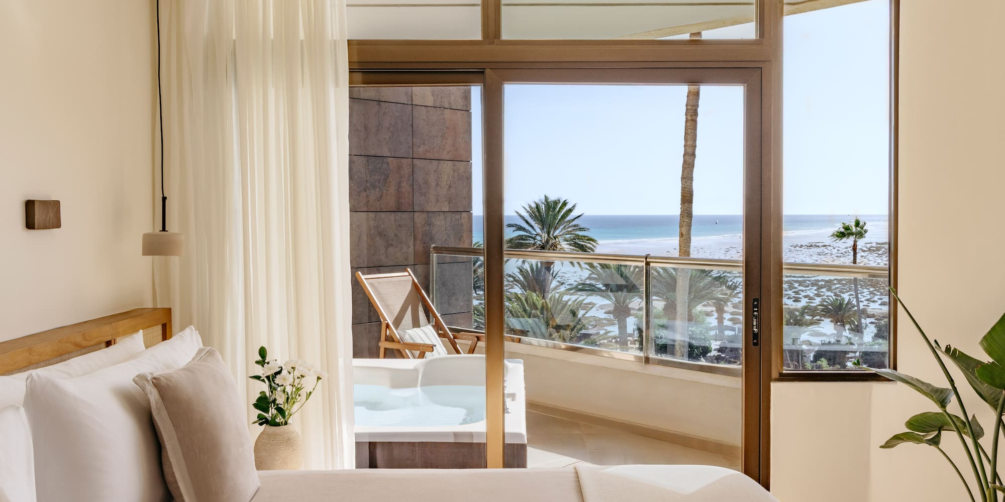 a bedroom with a view of the ocean and a jacuzzi