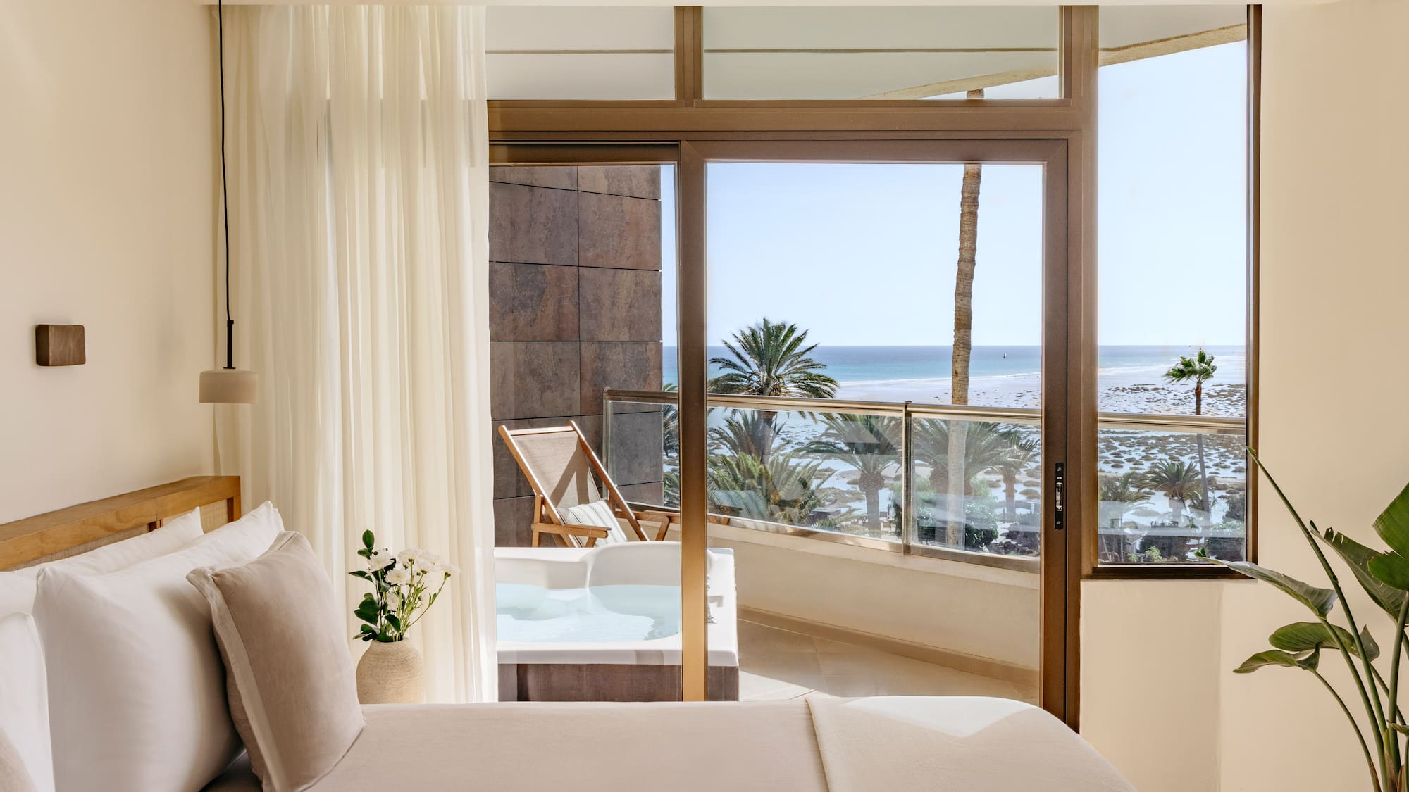 a bedroom with a view of the ocean and a jacuzzi