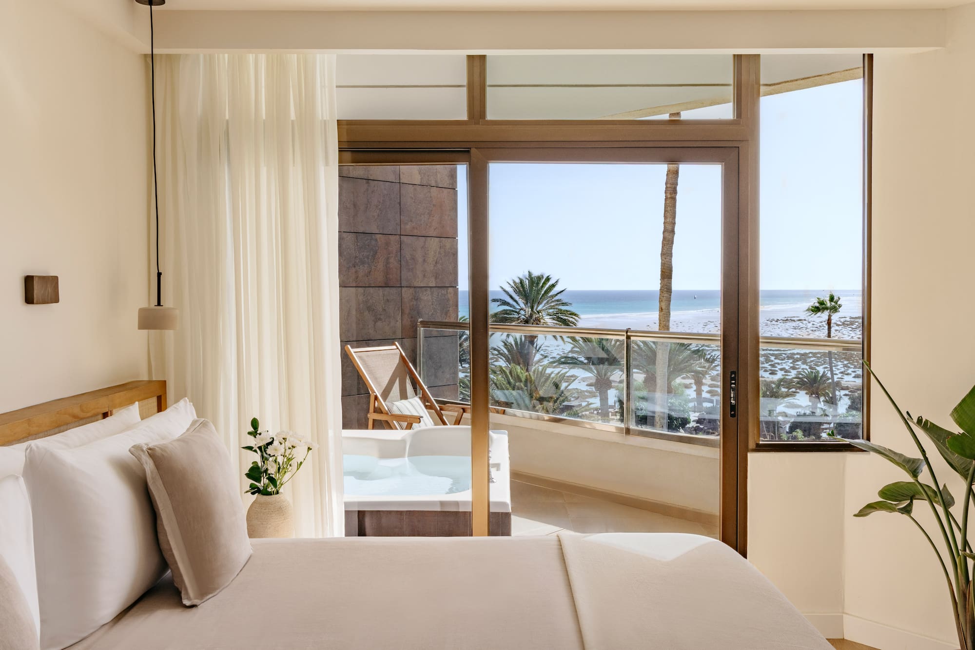 a bedroom with a view of the ocean and a jacuzzi