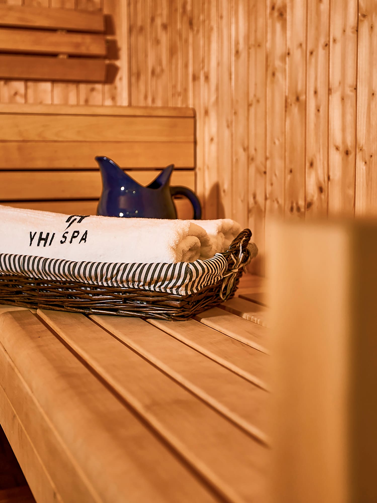 a basket of towels and a pitcher on a wooden bench