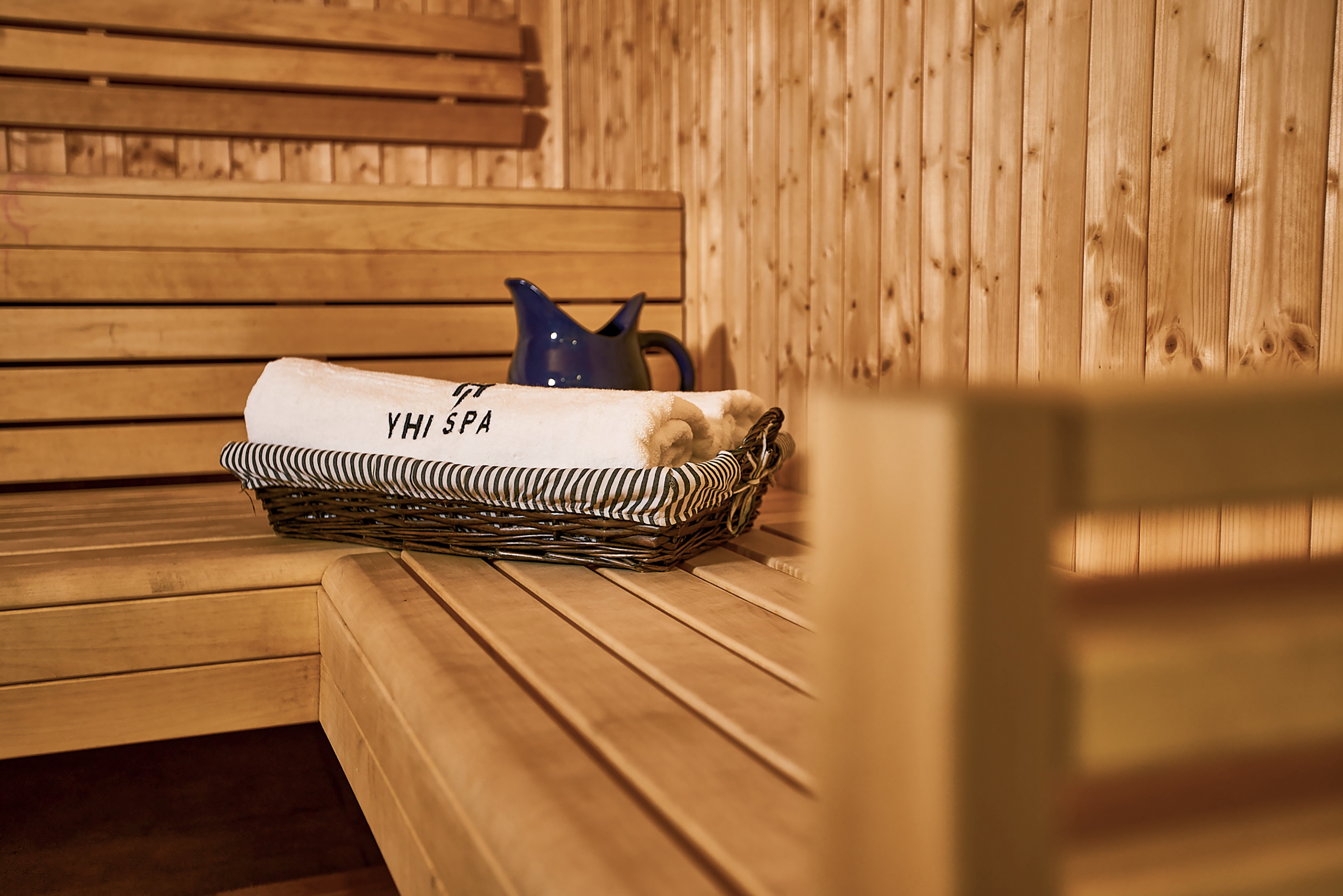 a basket of towels and a pitcher on a wooden bench