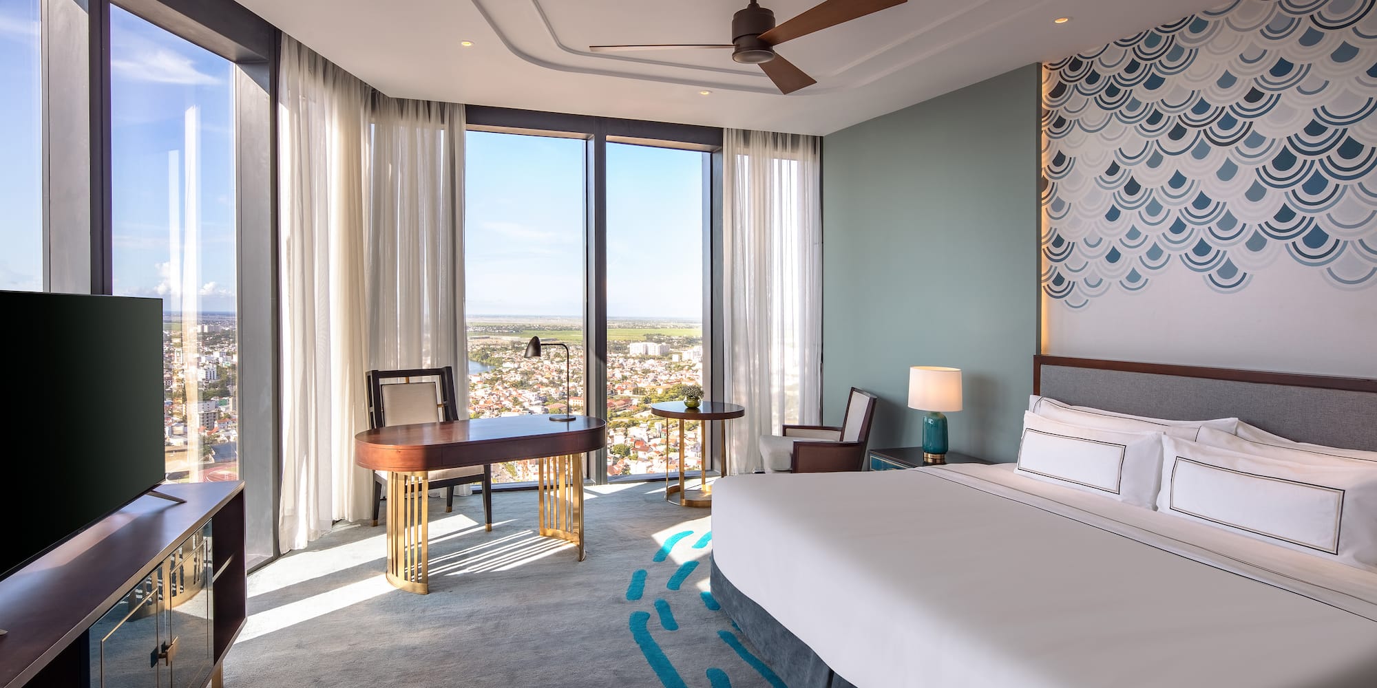 a room with a bed and a desk and a fan