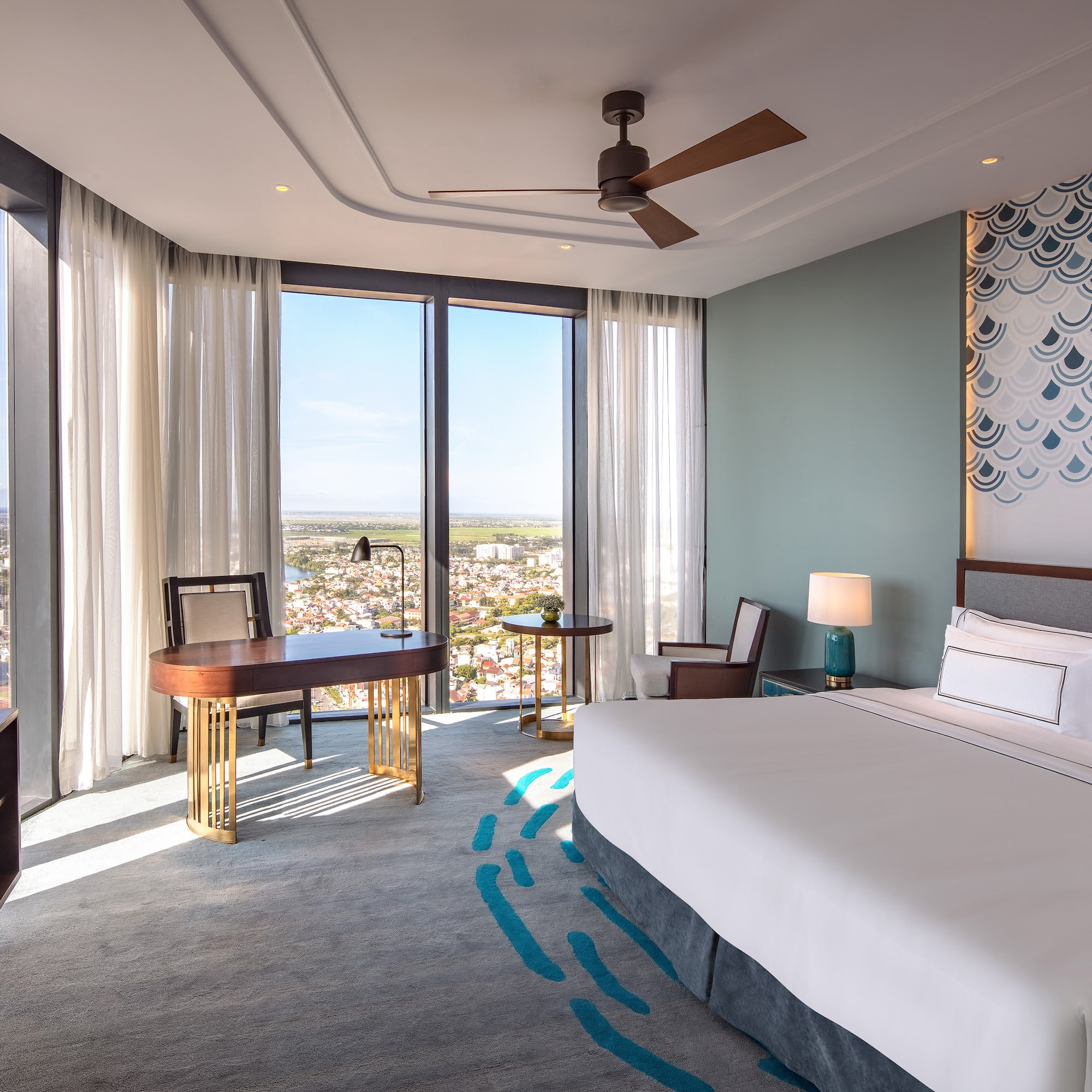 a room with a bed and a desk and a fan