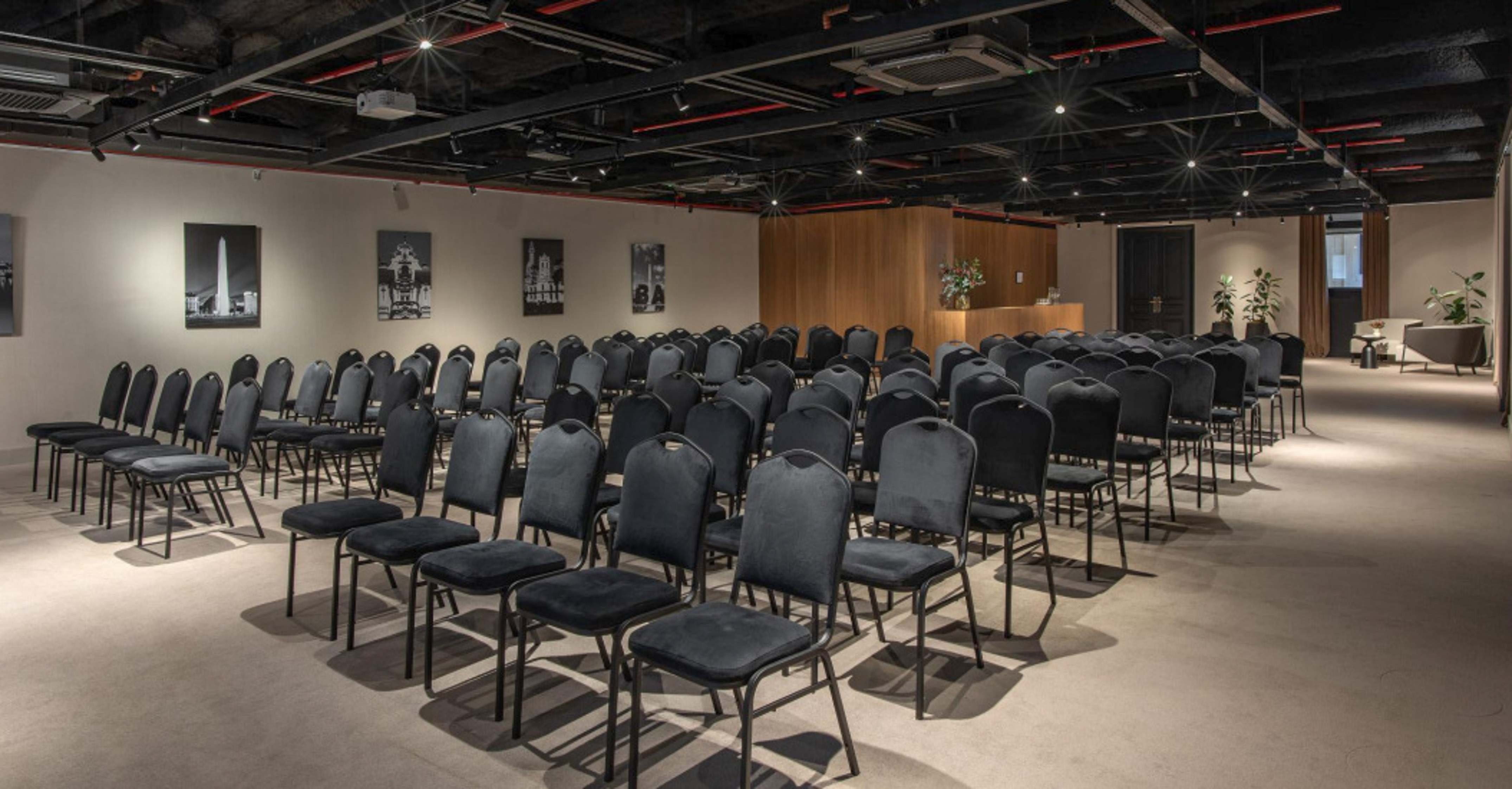 Modern conference room with black chairs, projector, and wooden features. Event venue.