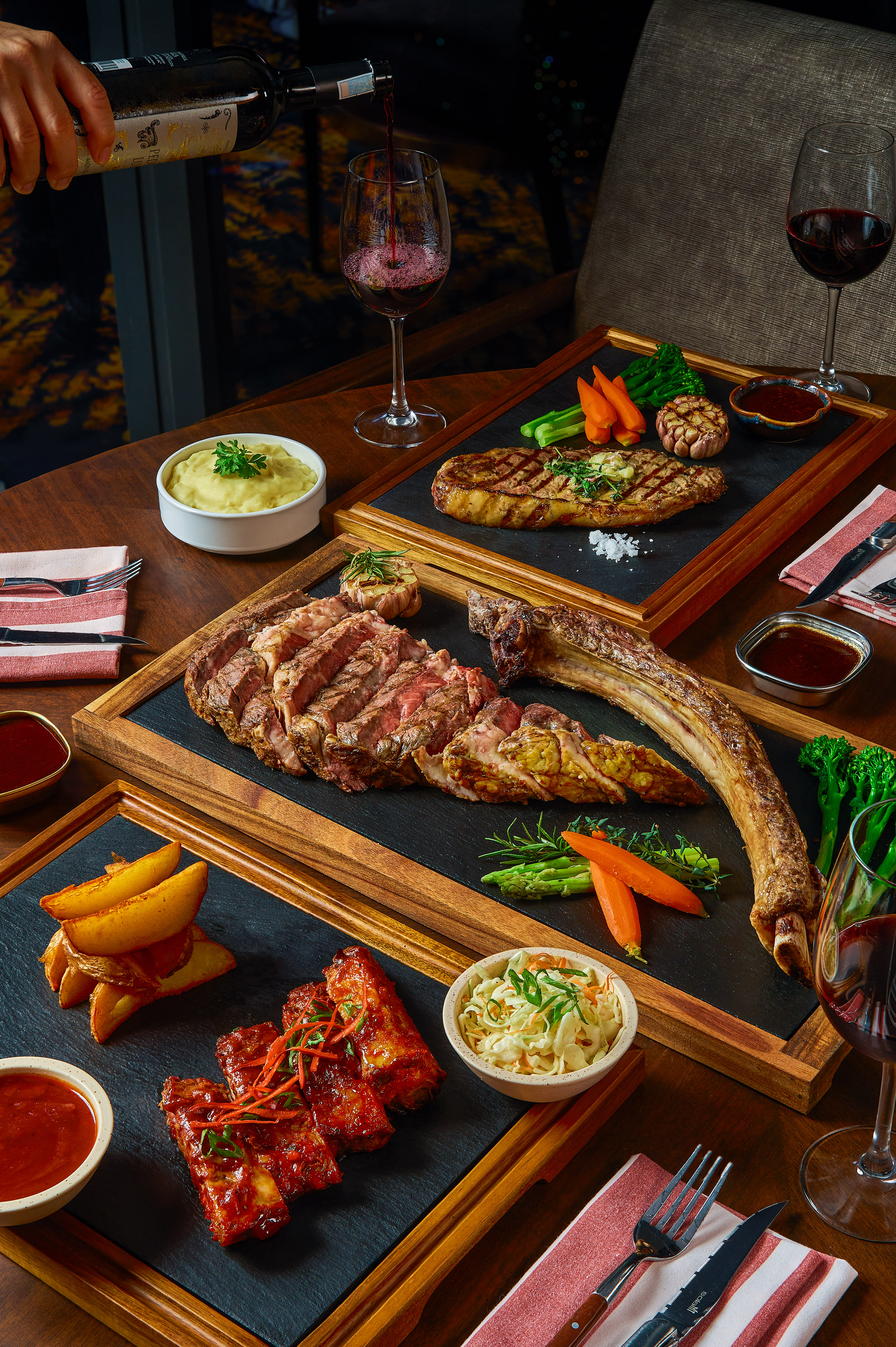 Tomahawk steak, grilled steak, BBQ ribs dinner with sides and red wine.
