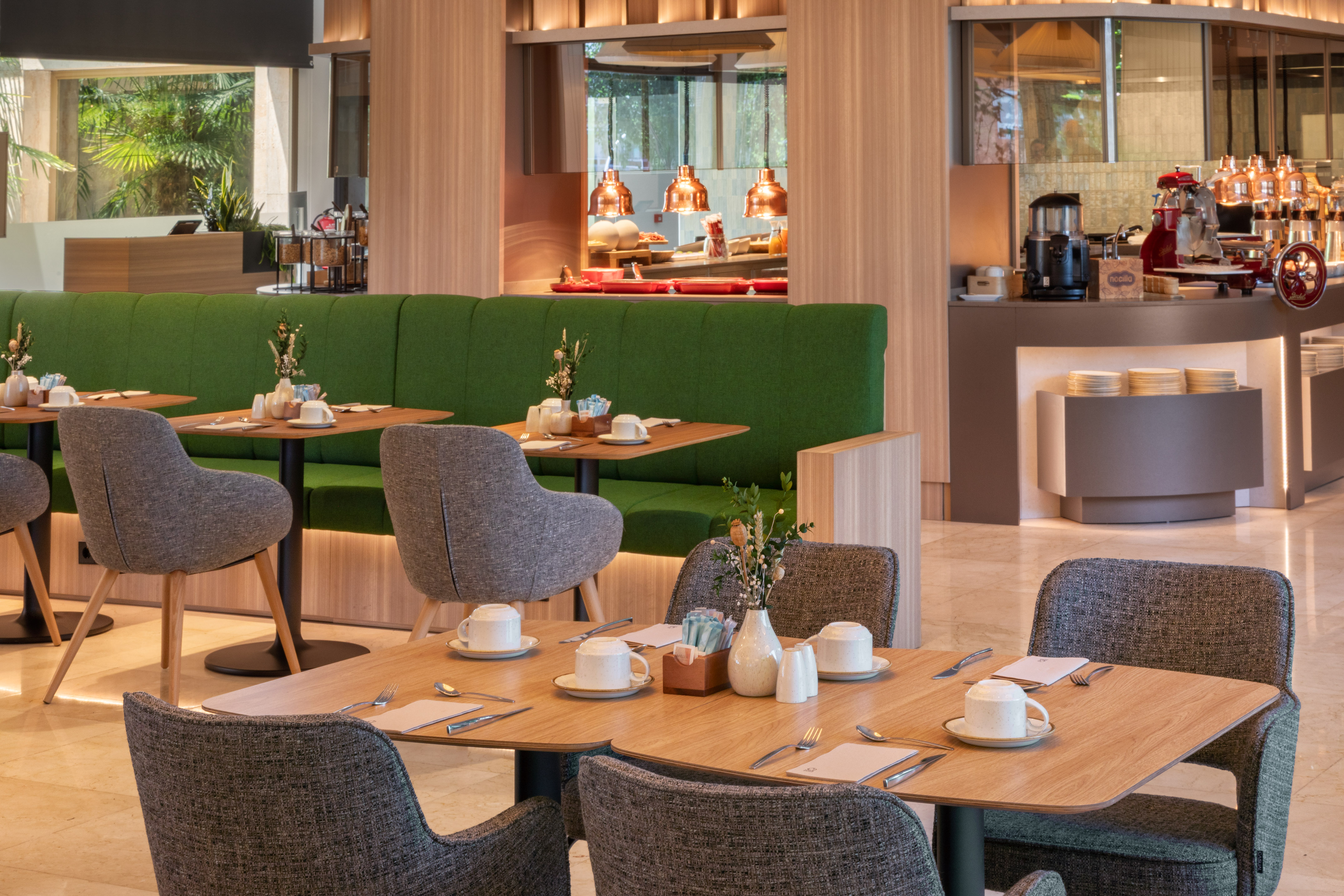 Modern hotel restaurant breakfast buffet with green banquette seating.