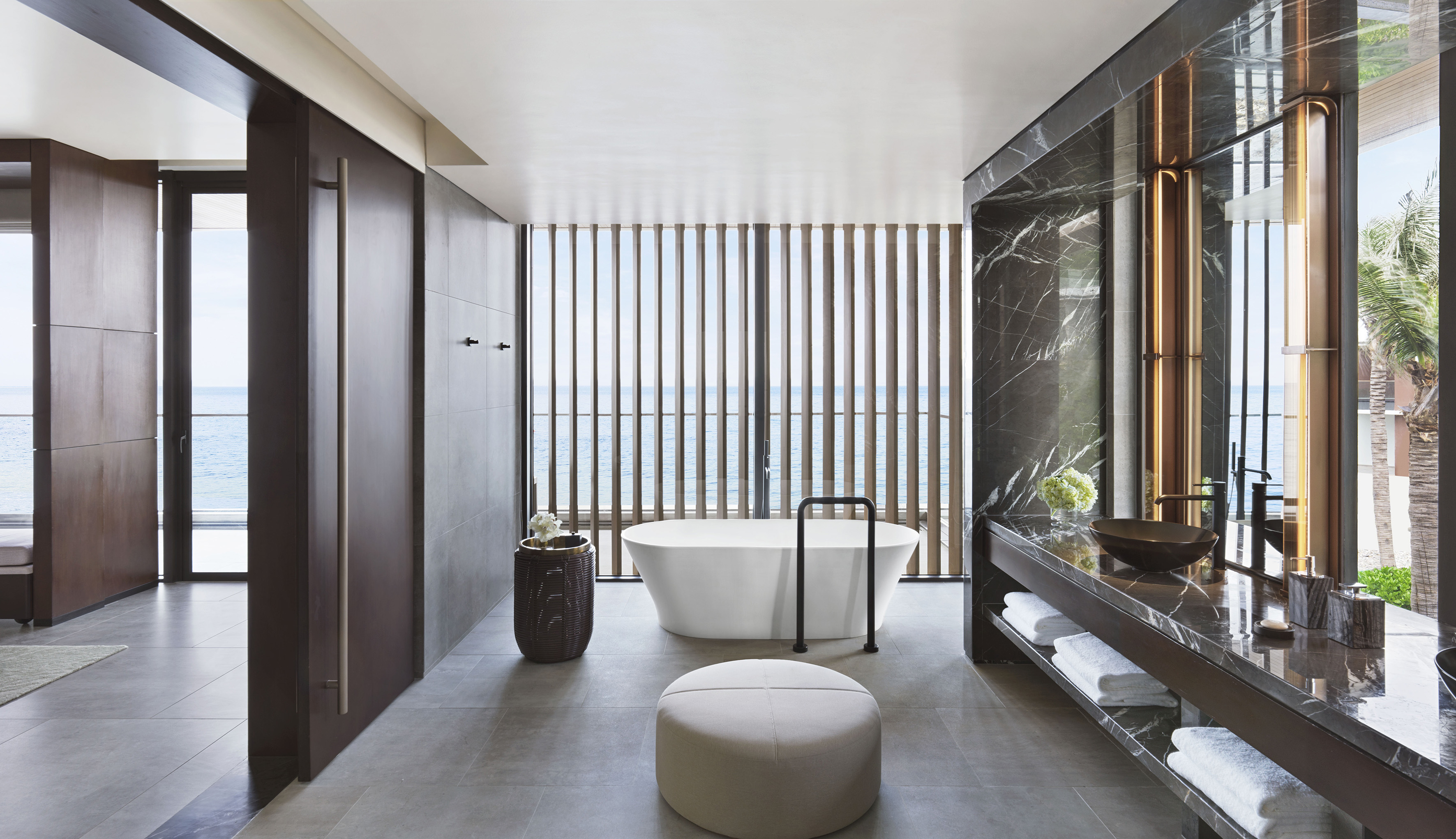 Luxury bathroom with ocean view, freestanding tub, and dark marble vanity.