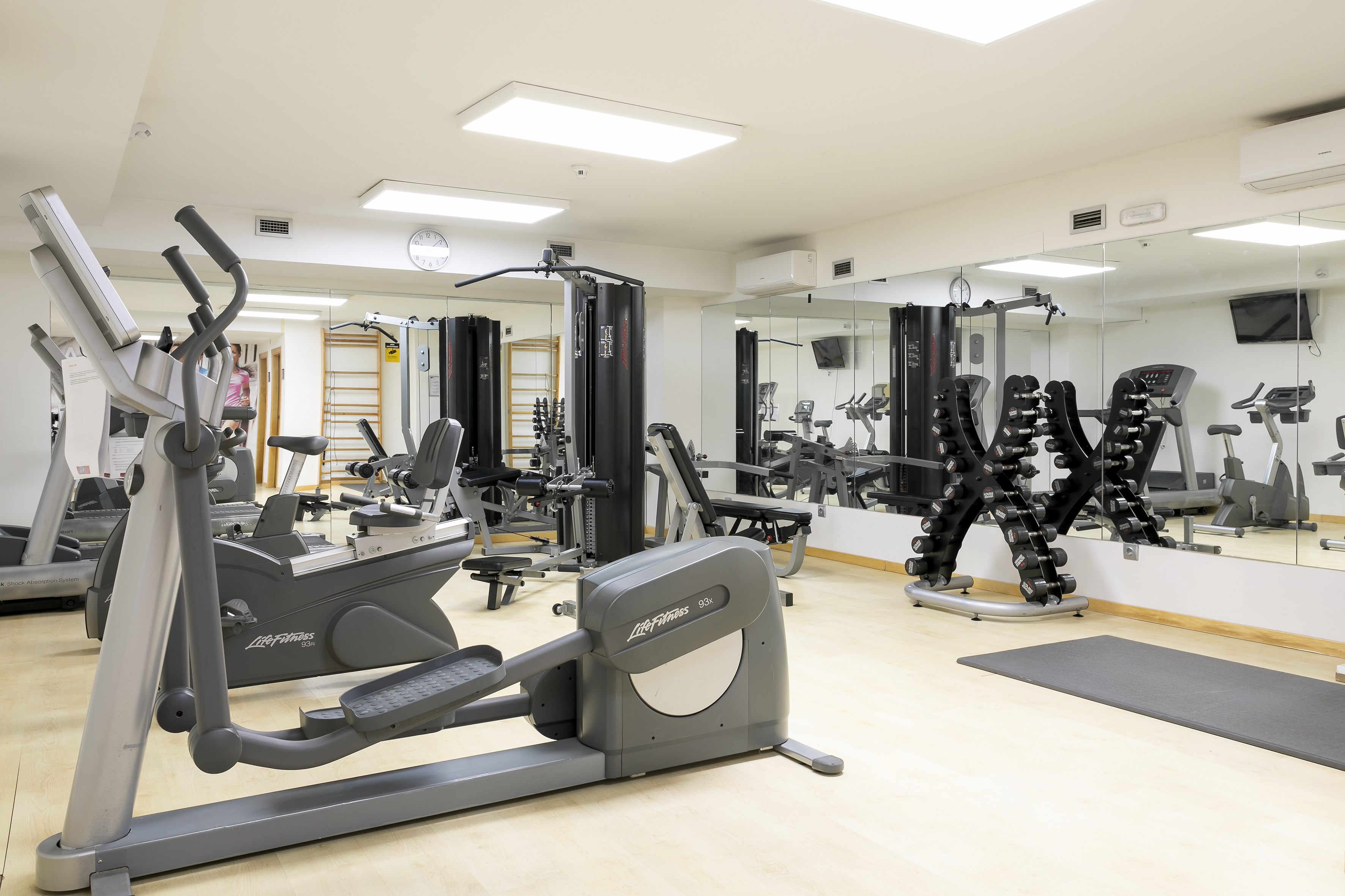 Modern gym with Life Fitness cardio, weight machines, and dumbbells.